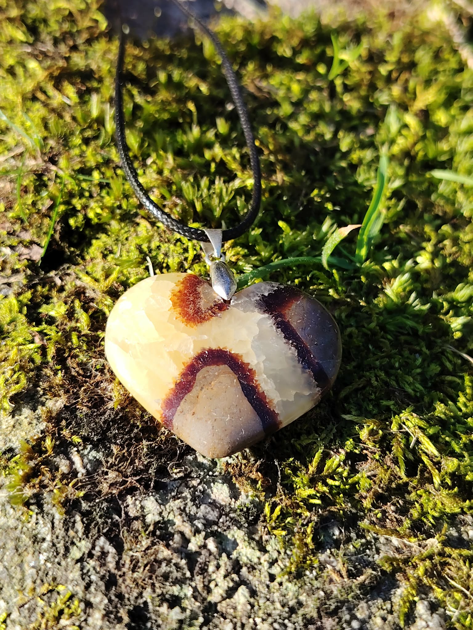 Pendentif cœur en septaria photographié sur tapis de mousse en forêt bretonne, pierre naturelle associée à l’enracinement, à la solidité intérieure et à l’harmonie émotionnelle.