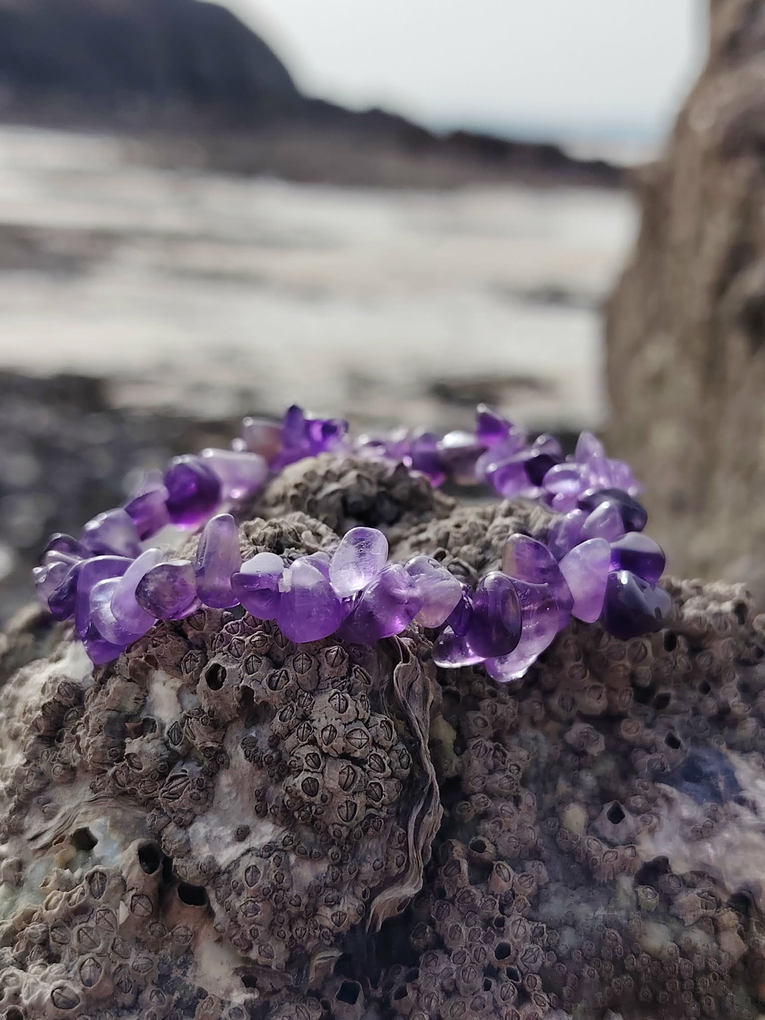 Bracelet améthyste baroque sur rocher granitique face à la mer en Bretagne, bracelet en pierre naturelle violet pour sérénité et intuition