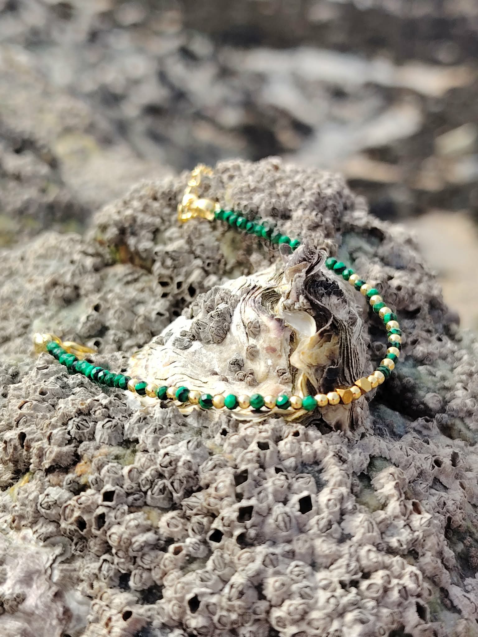 Bracelet fin en malachite facettée et cuivre plaqué or sur coquillage et rocher brut en Bretagne, composition minérale élégante