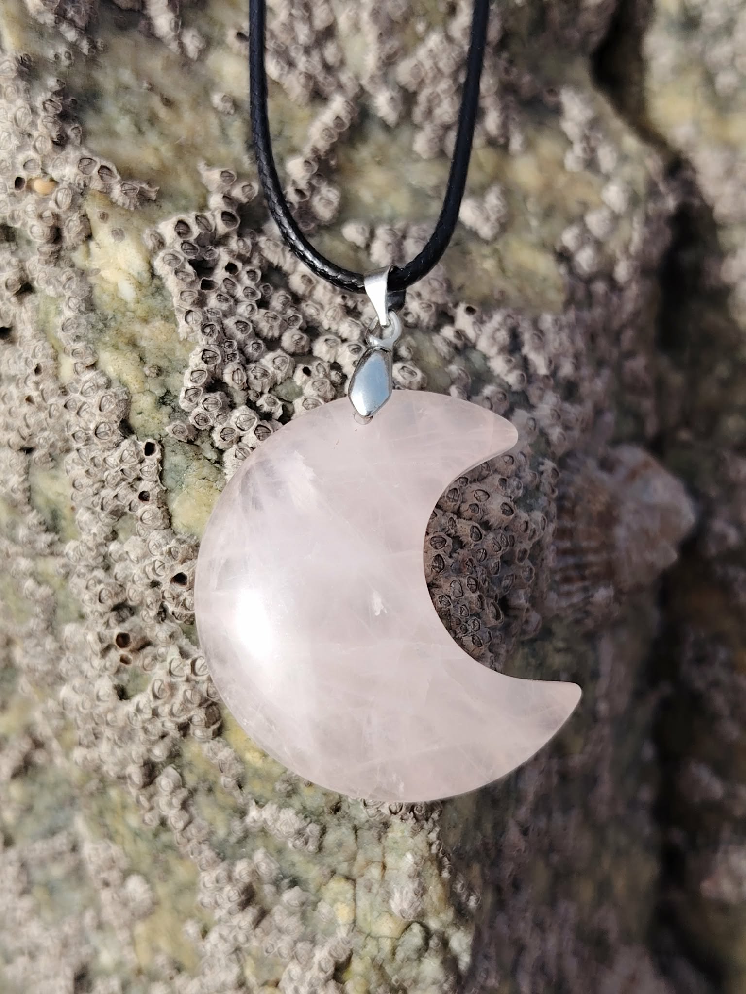 Pendentif lune en quartz rose naturel sur roche bretonne, bijou tendre aux nuances rosées associé au réconfort, à l’écoute de soi et à l’équilibre émotionnel.