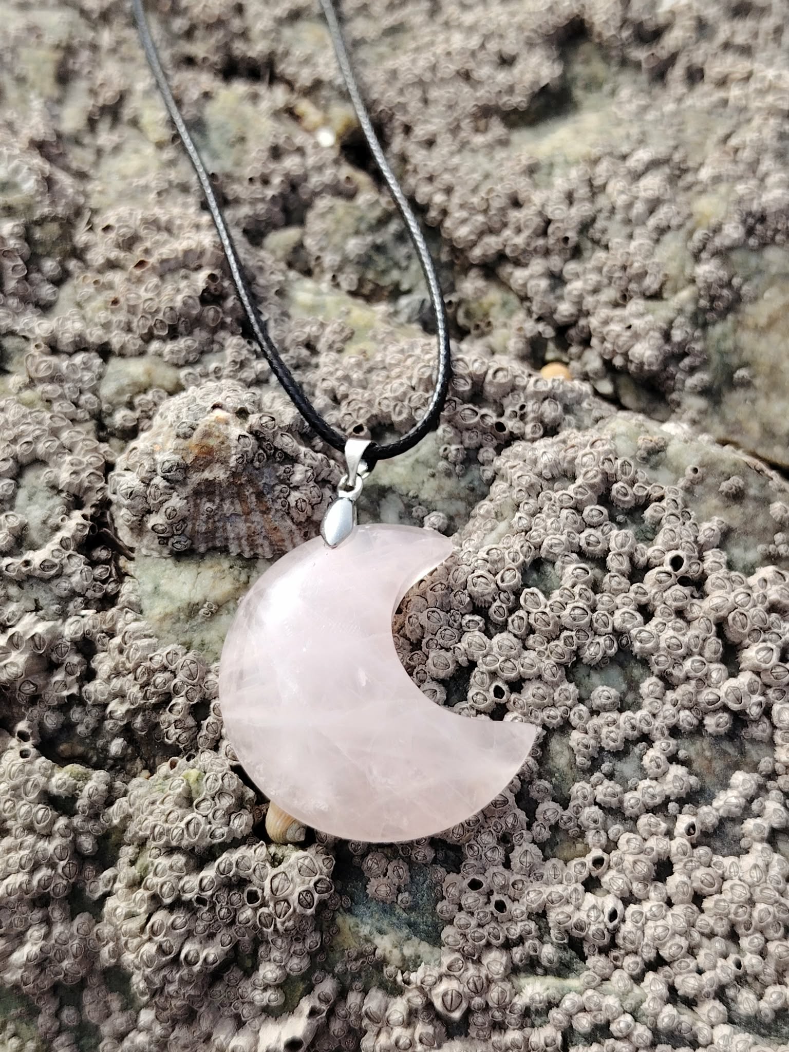 Pendentif lune en quartz rose naturel sur roche bretonne, photo Bretagne, bijou délicat lié à la bienveillance, au réconfort affectif et à la sérénité.