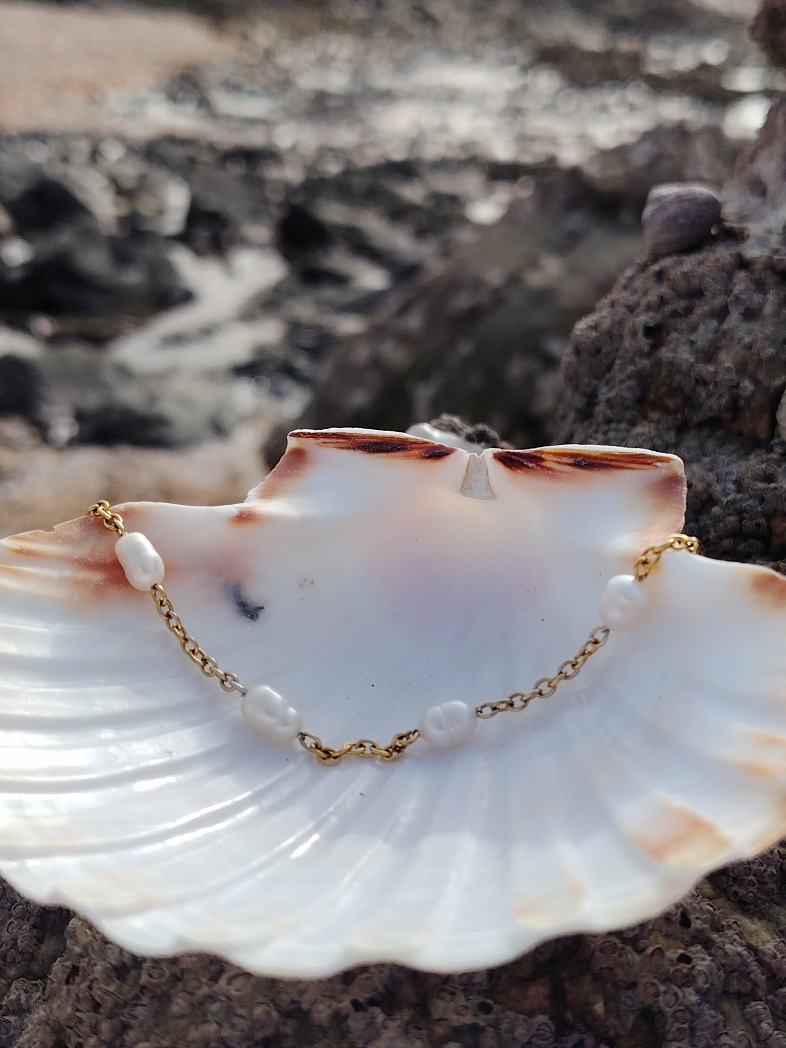 Bracelet perles d’eau douce et nacre sur coquillage et rochers en Bretagne, calme intérieur, féminité et délicatesse