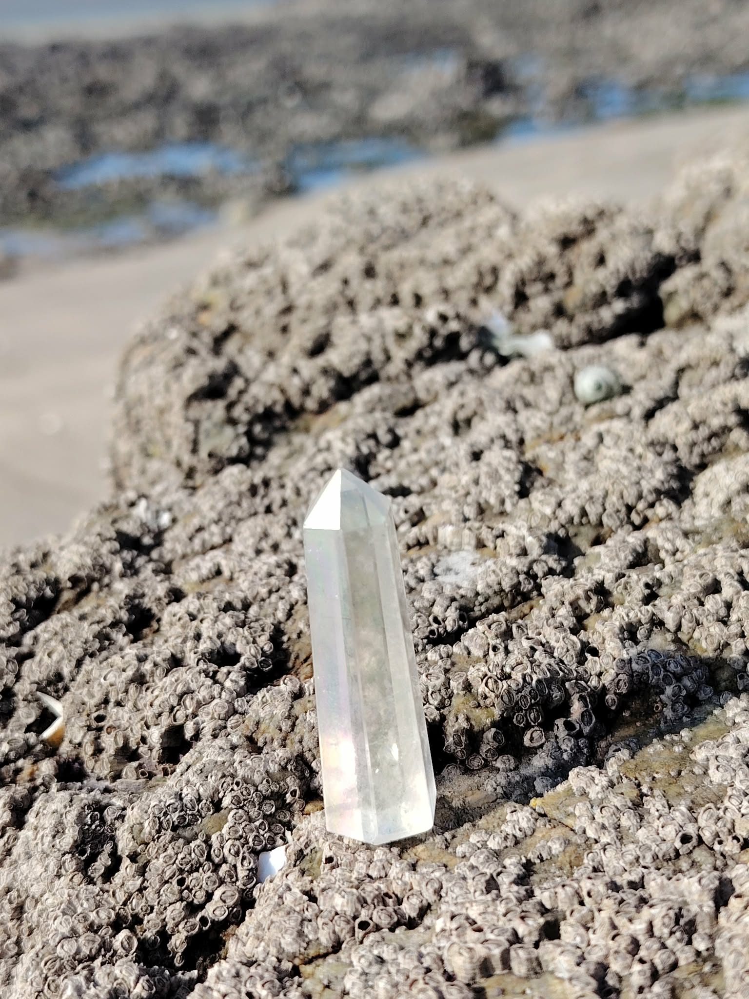 Pointe Angel Aura dressée sur les rochers face à la mer en Bretagne, cristal aux reflets célestes associé à l’apaisement, à la lucidité et à la présence à soi.