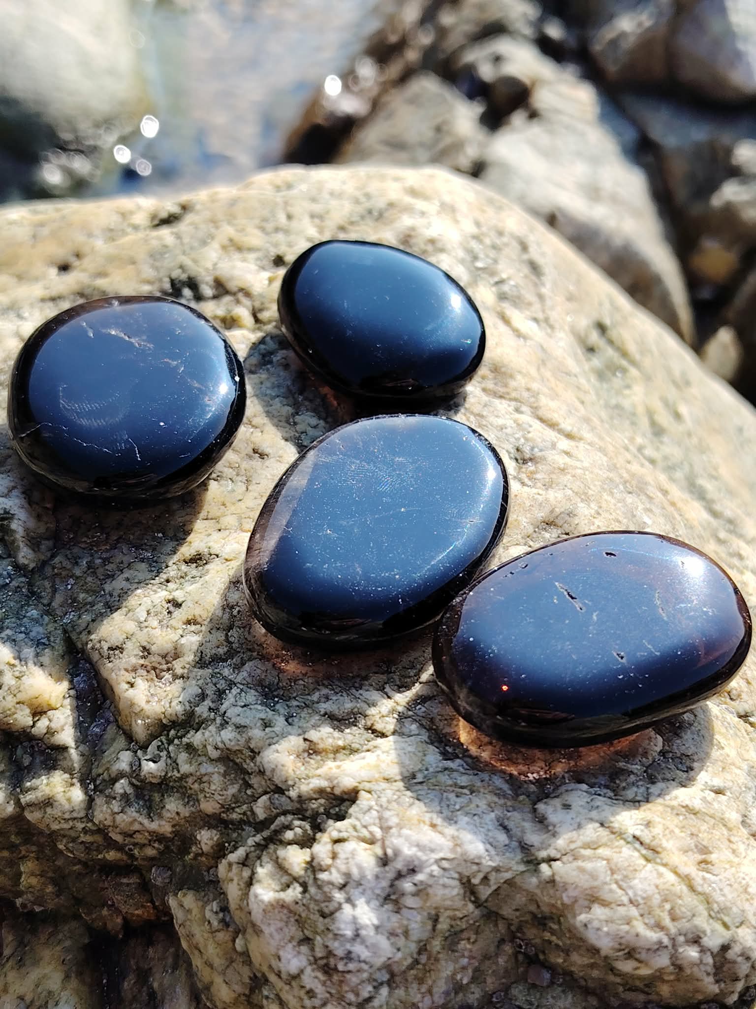 Galets en quartz fumé posés sur les rochers en Bretagne près de l’eau, pierres naturelles associées à l’enracinement, à la paix du mental et à la solidité intérieure.