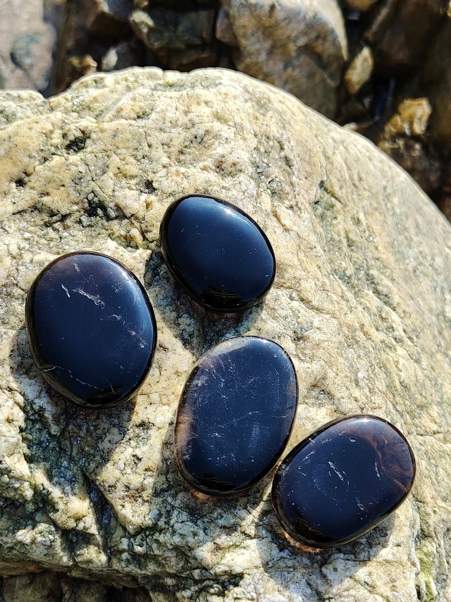 Galets en quartz fumé posés sur un rocher en Bretagne, pierres naturelles évoquant la maîtrise de soi, la tranquillité intérieure et la profondeur apaisante.