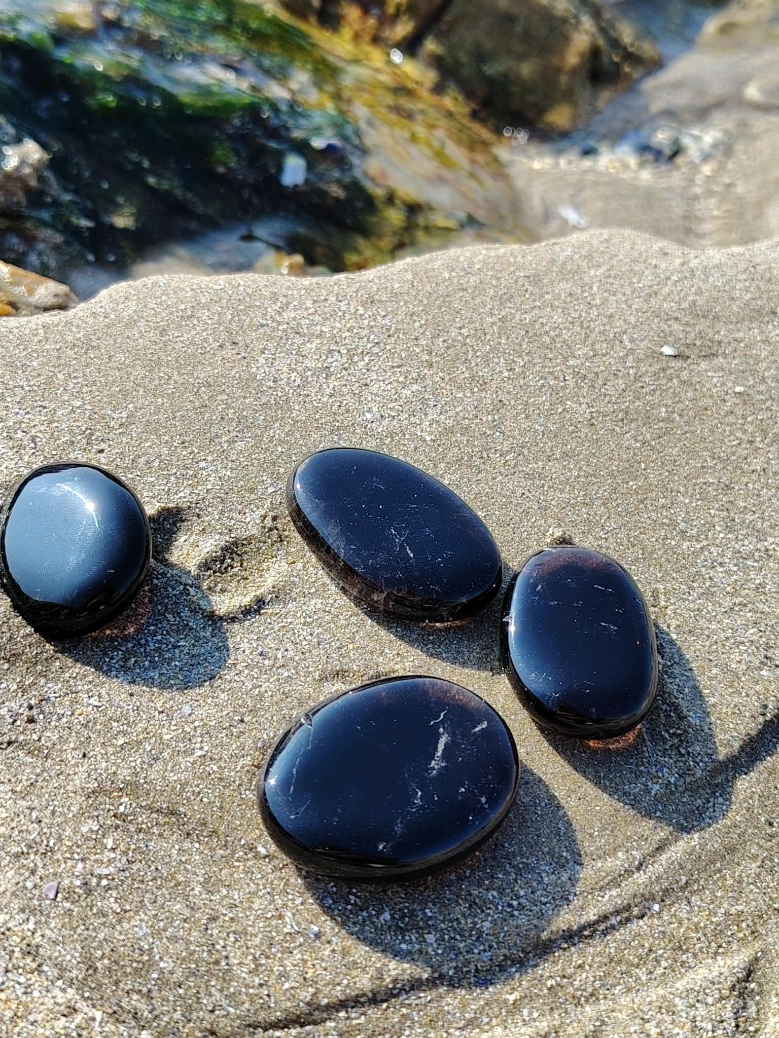 Galets en quartz fumé posés sur la roche en Bretagne près de l’eau et du sable, pierres naturelles associées à l’équilibre émotionnel, au calme et à l’ancrage doux.