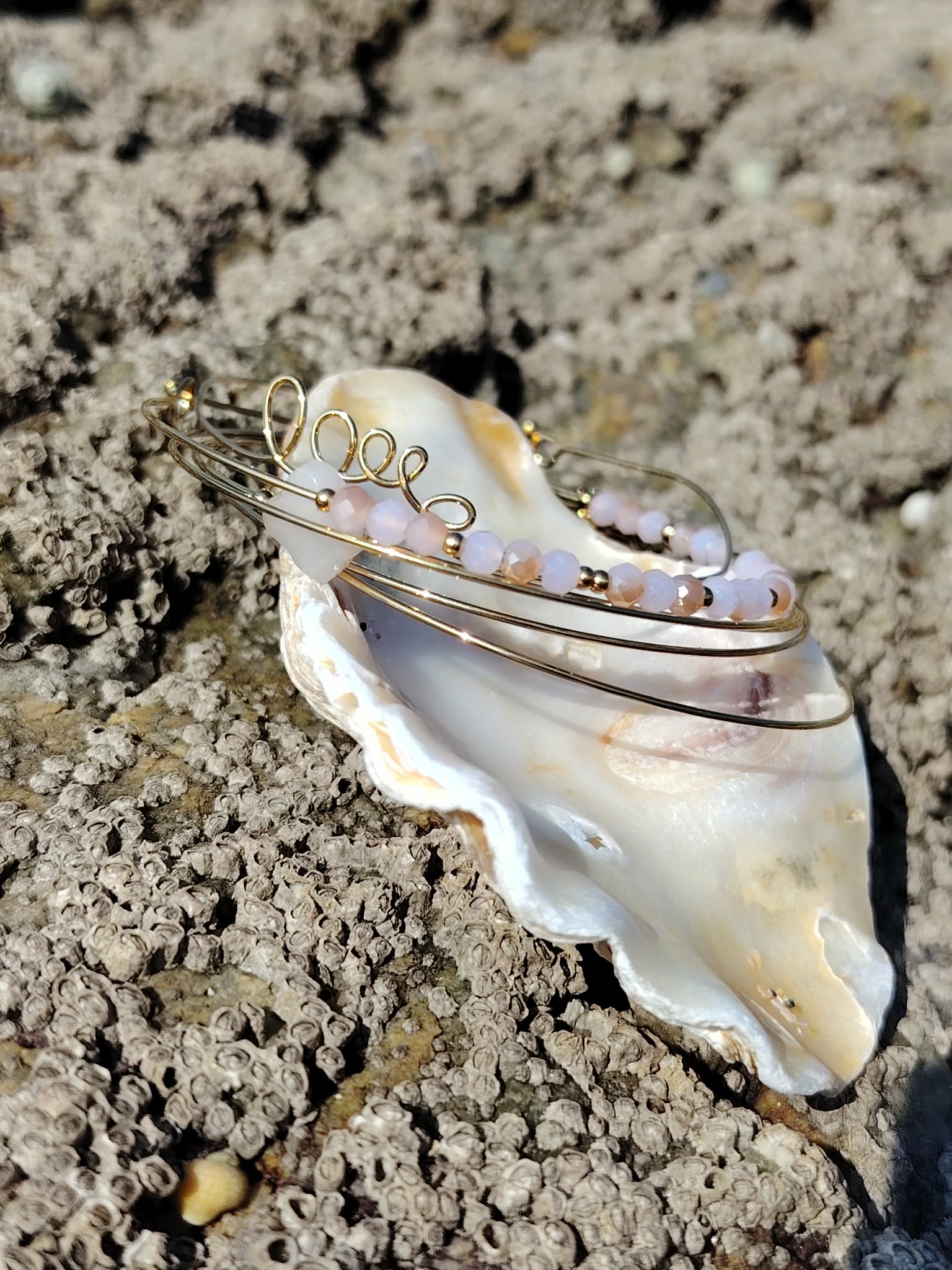 Bracelet semainier quartz rose et acier inoxydable doré photographié sur rochers en Bretagne, éclat doux et charme naturel