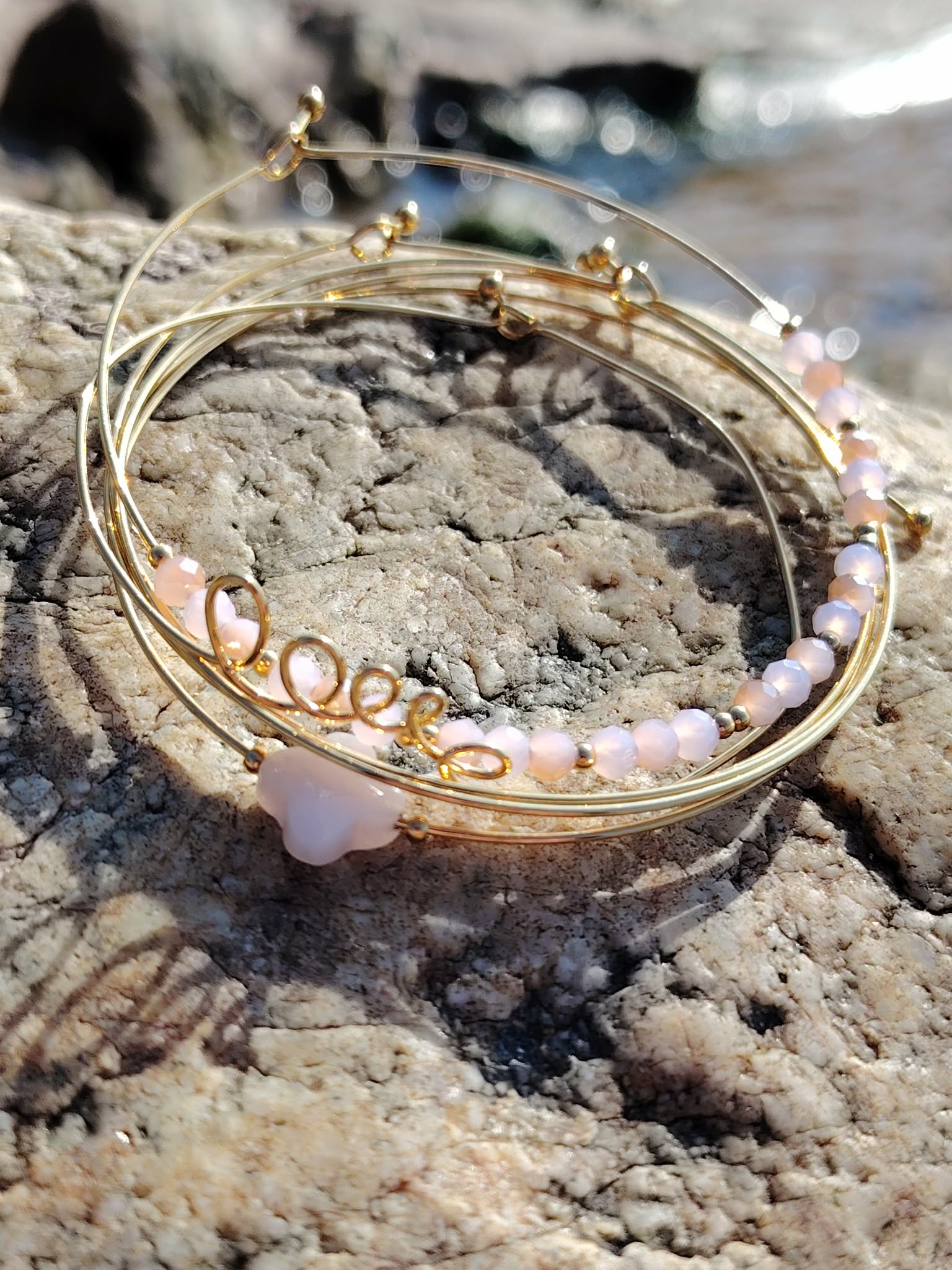 Bracelet semainier Love quartz rose en acier inoxydable sur rochers en Bretagne, bracelet féminin au design minimaliste