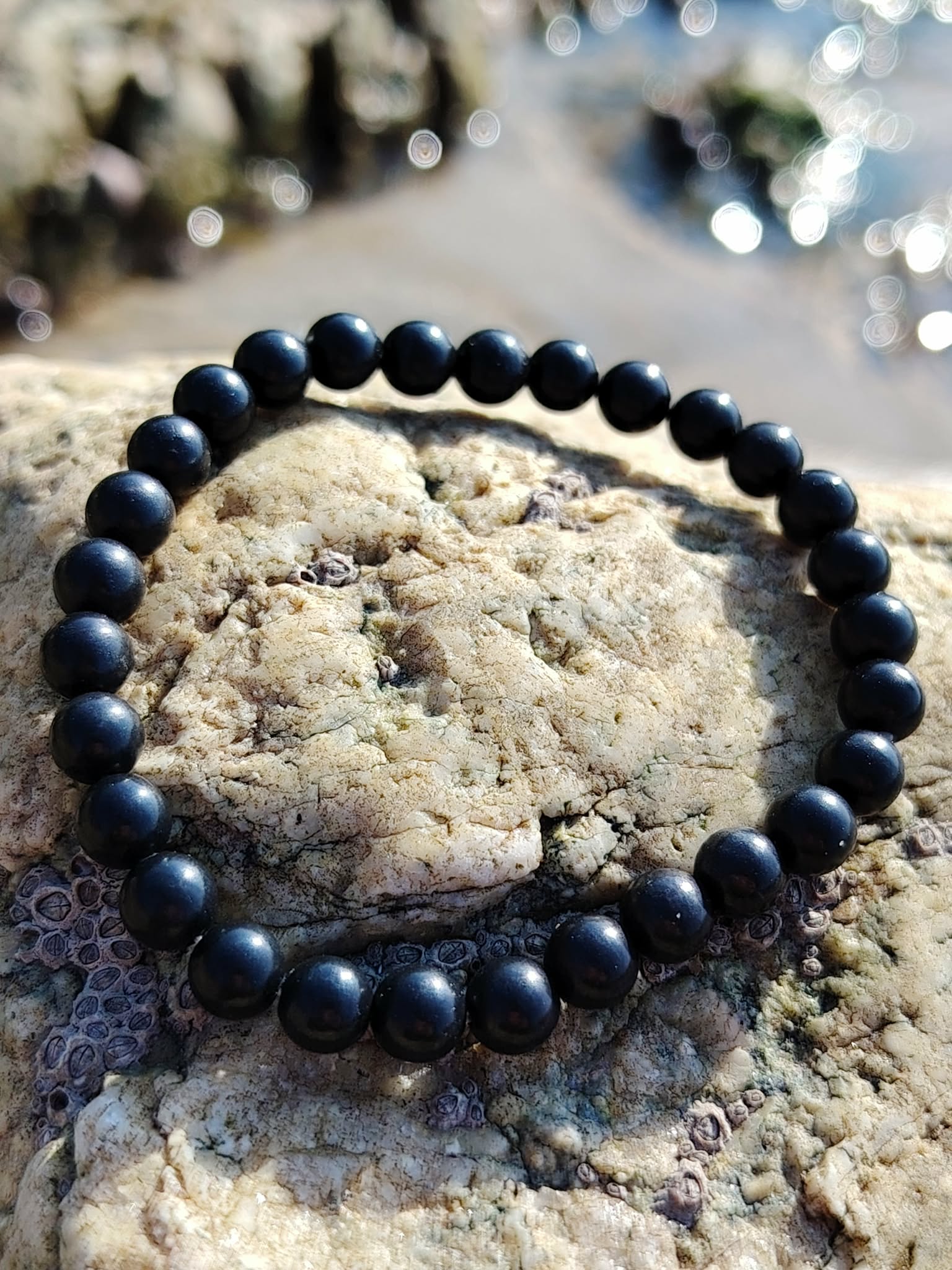Bracelet shungite 6 mm noir profond sur pierre texturée, photo Bretagne, ancrage solide, protection discrète et esprit plus stable