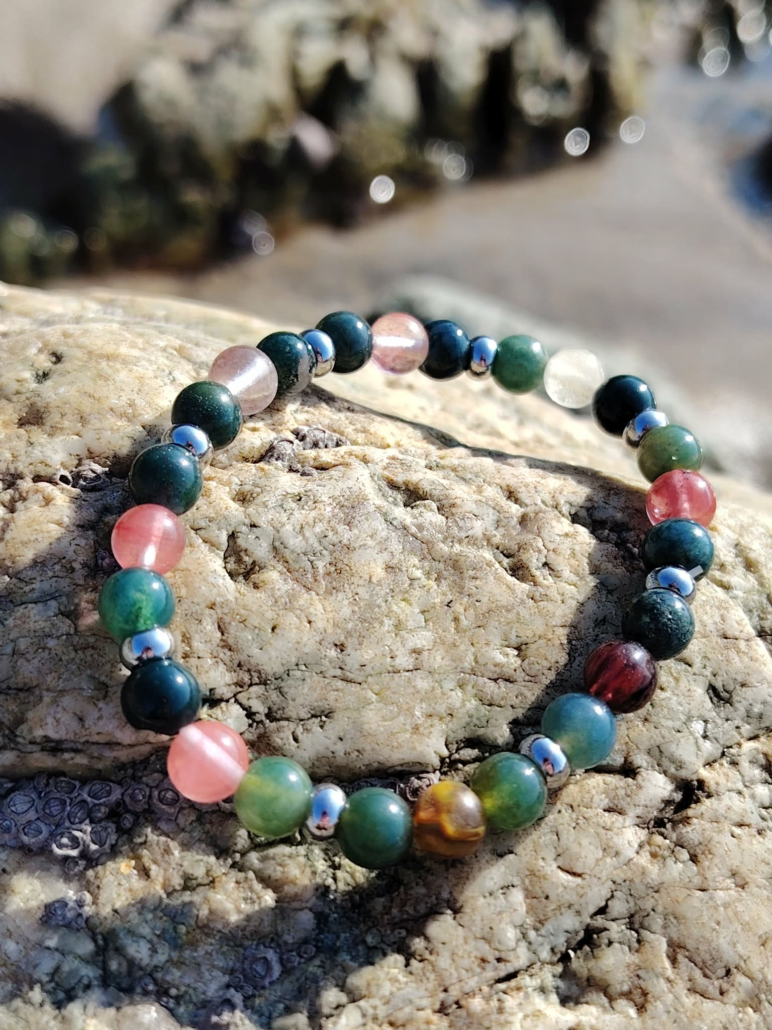 Bracelet chakra cœur 6 mm en agate mousse et tourmaline melon d’eau sur rochers en Bretagne près de l’eau, harmonie affective, douceur du cœur et apaisement intérieur
