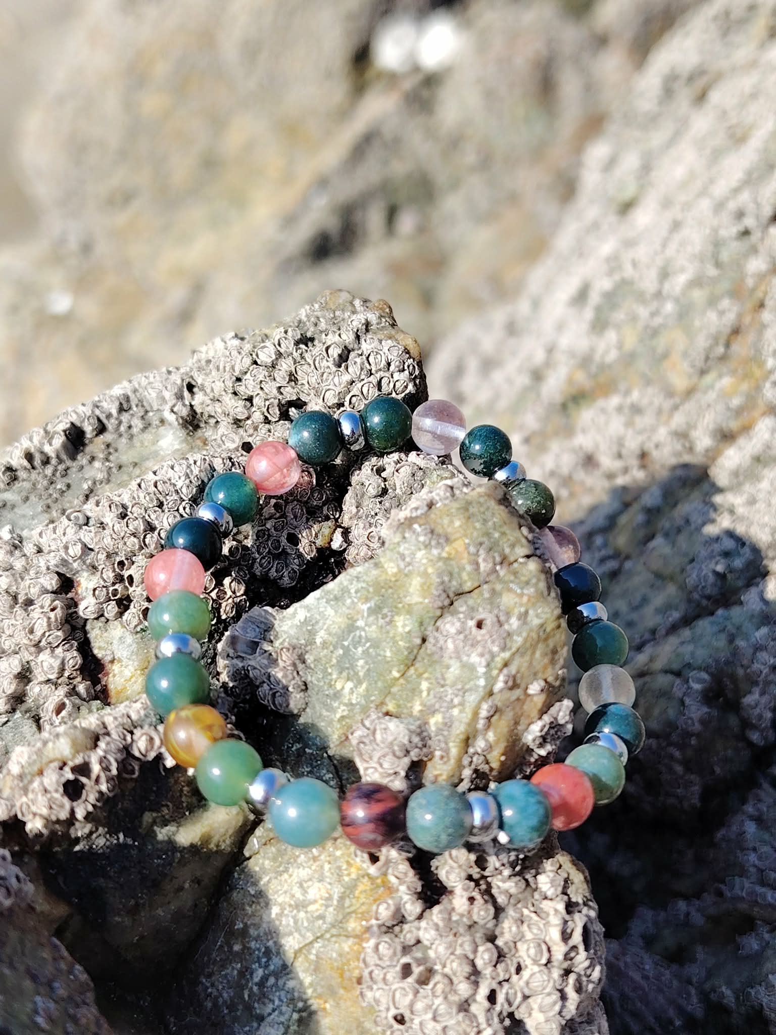 Bracelet chakra cœur 6 mm posé entre les rochers en Bretagne, agate mousse et tourmaline melon d’eau pour lien apaisé, stabilité du ressenti et douceur relationnelle