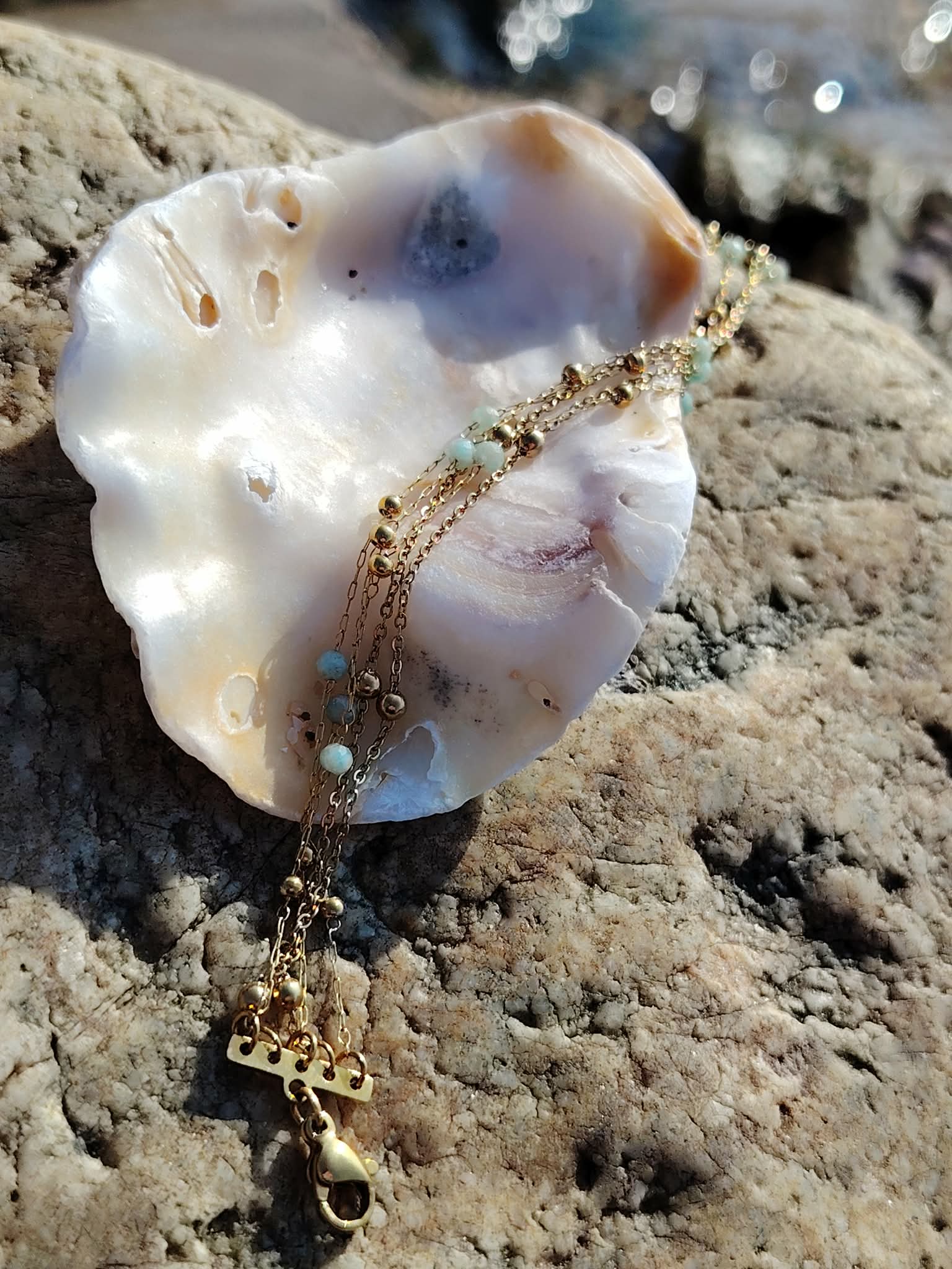 Bracelet doré multi-rangs en amazonite facettée sur fond blanc, fines chaînes élégantes et perles bleu ciel au style raffiné