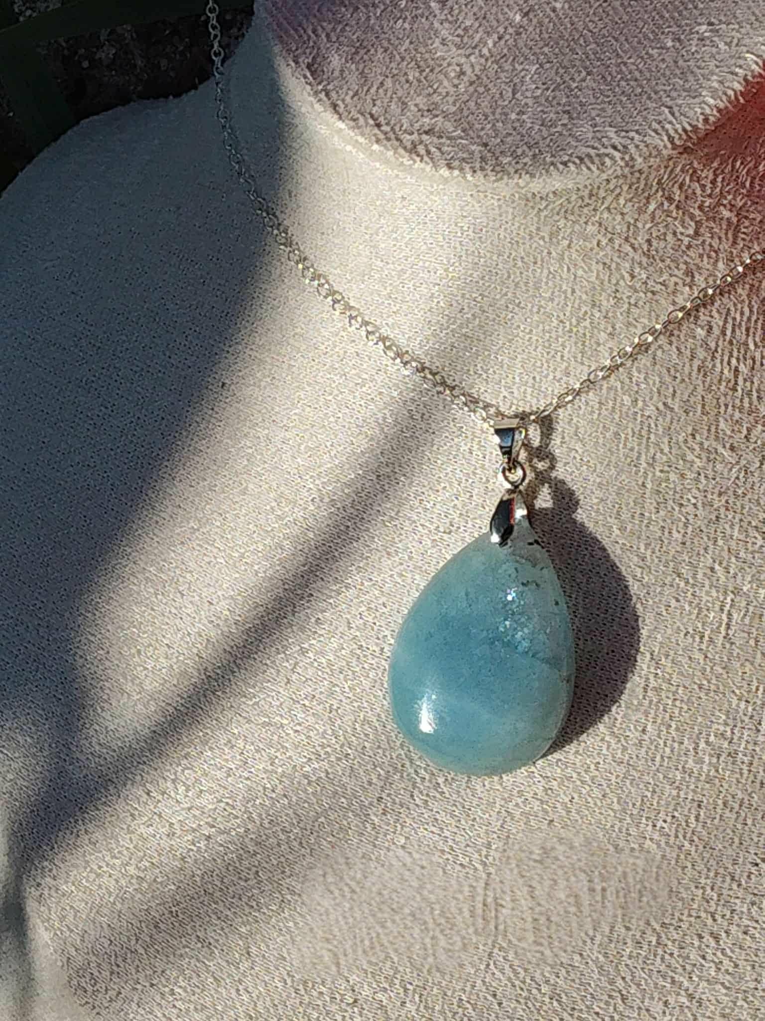 Pendentif en aigue-marine porté au cou sur chaîne argentée, bijou en pierre naturelle évoquant la douceur relationnelle, l’expression sincère et l’harmonie intérieure.