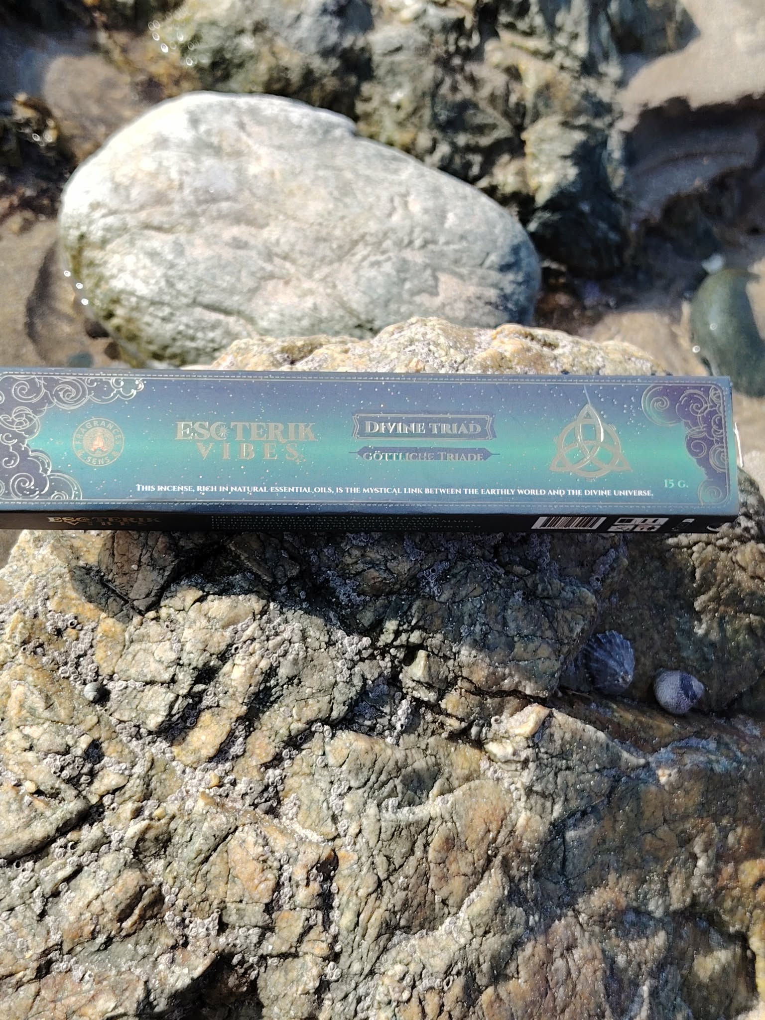 Boîte d’encens masala Triade 15 g Fragrance et Sens, posée sur rochers et coquillage en Bretagne, dans une ambiance spirituelle évoquant harmonie, recentrage et élévation.