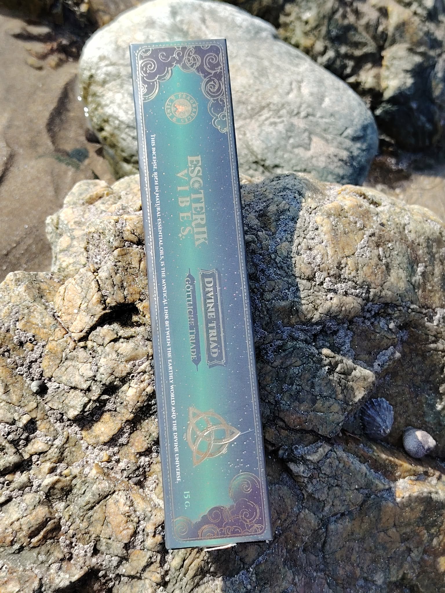 Boîte d’encens masala Triade 15 g Fragrance et Sens, posée sur les rochers en Bretagne, dans une ambiance minérale et spirituelle évoquant harmonie, recentrage et élévation.