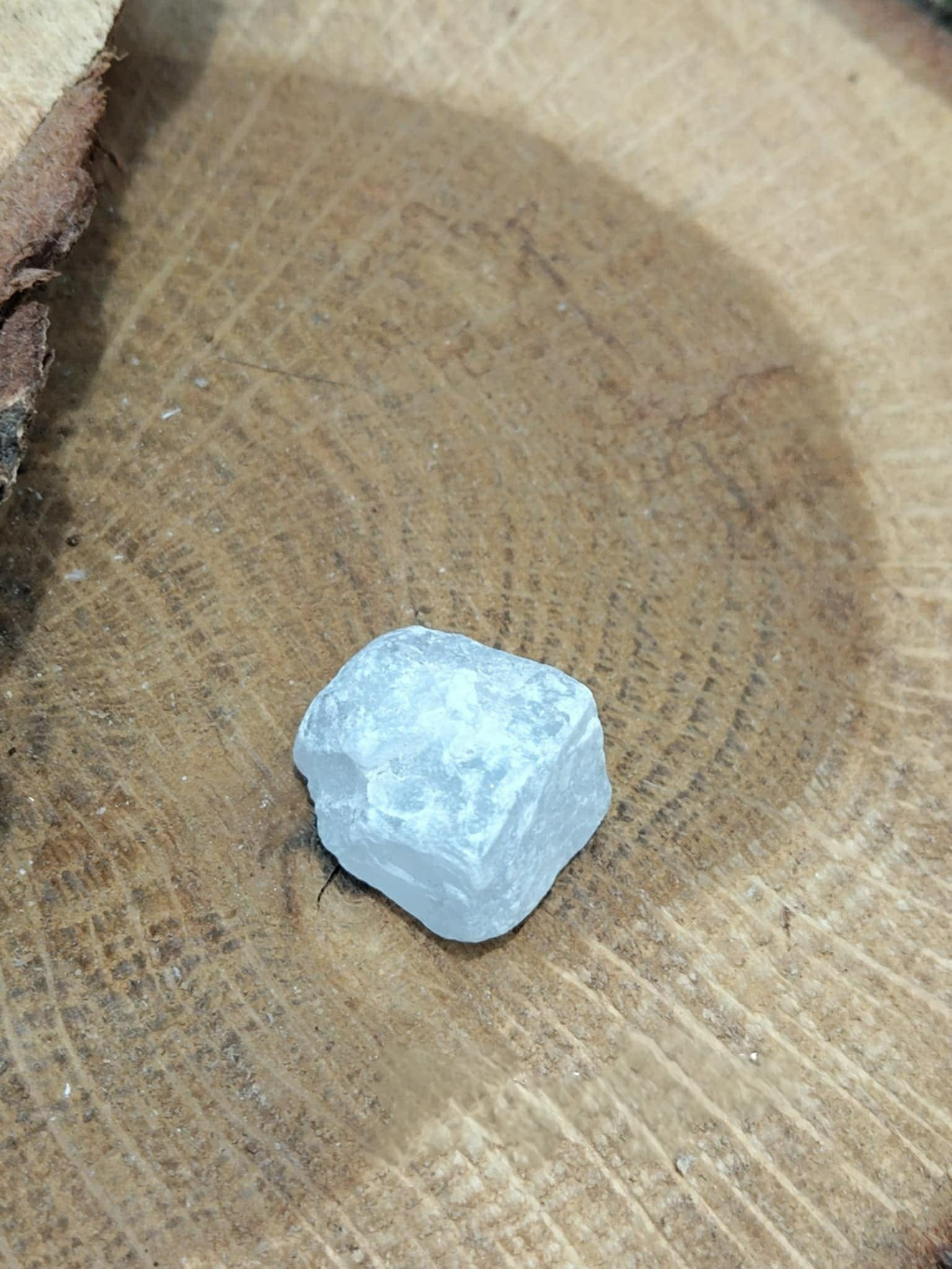 Pierre brute de célestine bleu ciel posée sur un support en bois, évoquant calme, réconfort et paix intérieure.