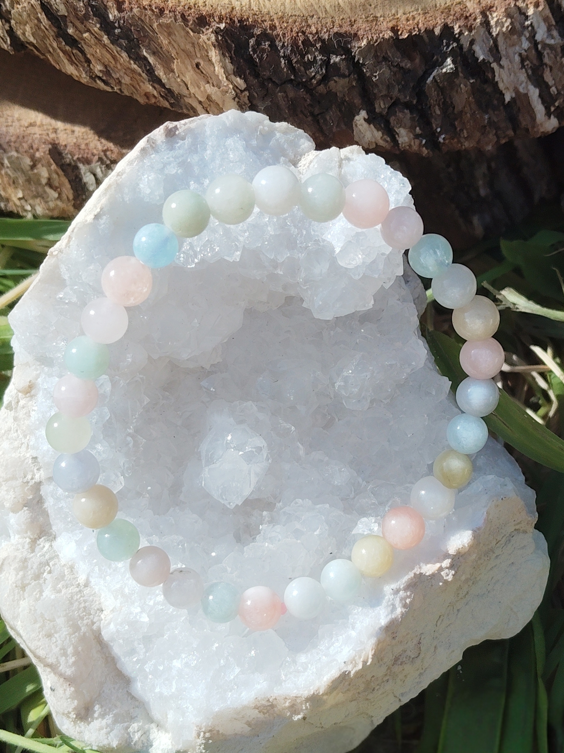 Bracelet Morganite 6 mm présenté sur géode blanche avec écorce et herbes, perles pastel aux reflets doux, bijou en pierre naturelle relié à la paix intérieure, à la tendresse et à l’équilibre émotionnel.