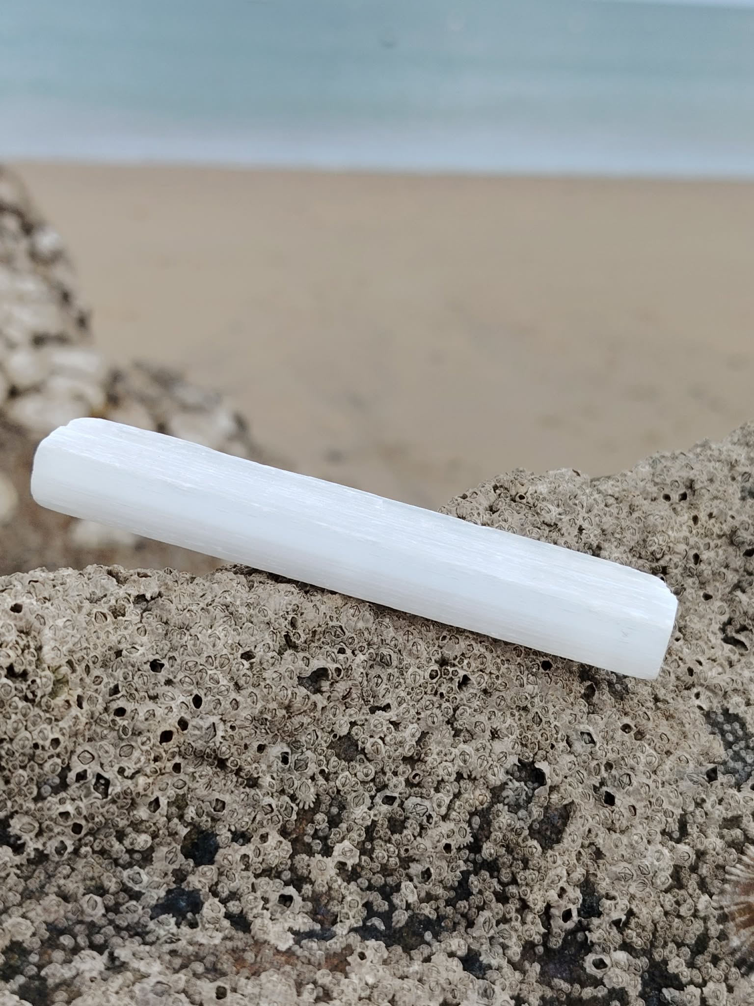 Baguette de sélénite montrée à la main en Bretagne, pierre satinée blanche aux reflets soyeux, clarté d’esprit et atmosphère sereine.