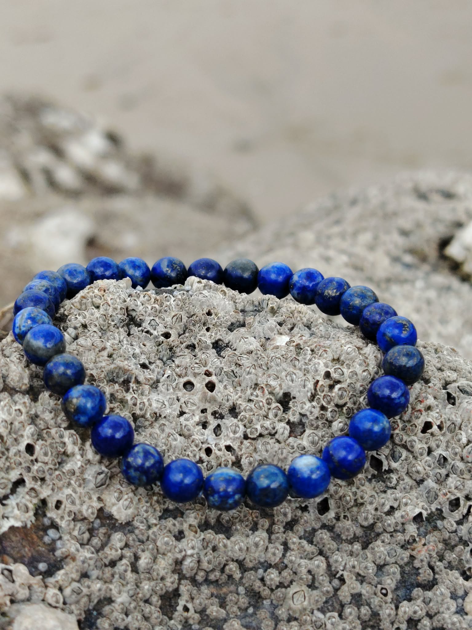 Bracelet Lapis Lazuli 6 mm sur pierre littorale texturée, perles bleu roi lumineuses, clarté mentale et communication authentique.