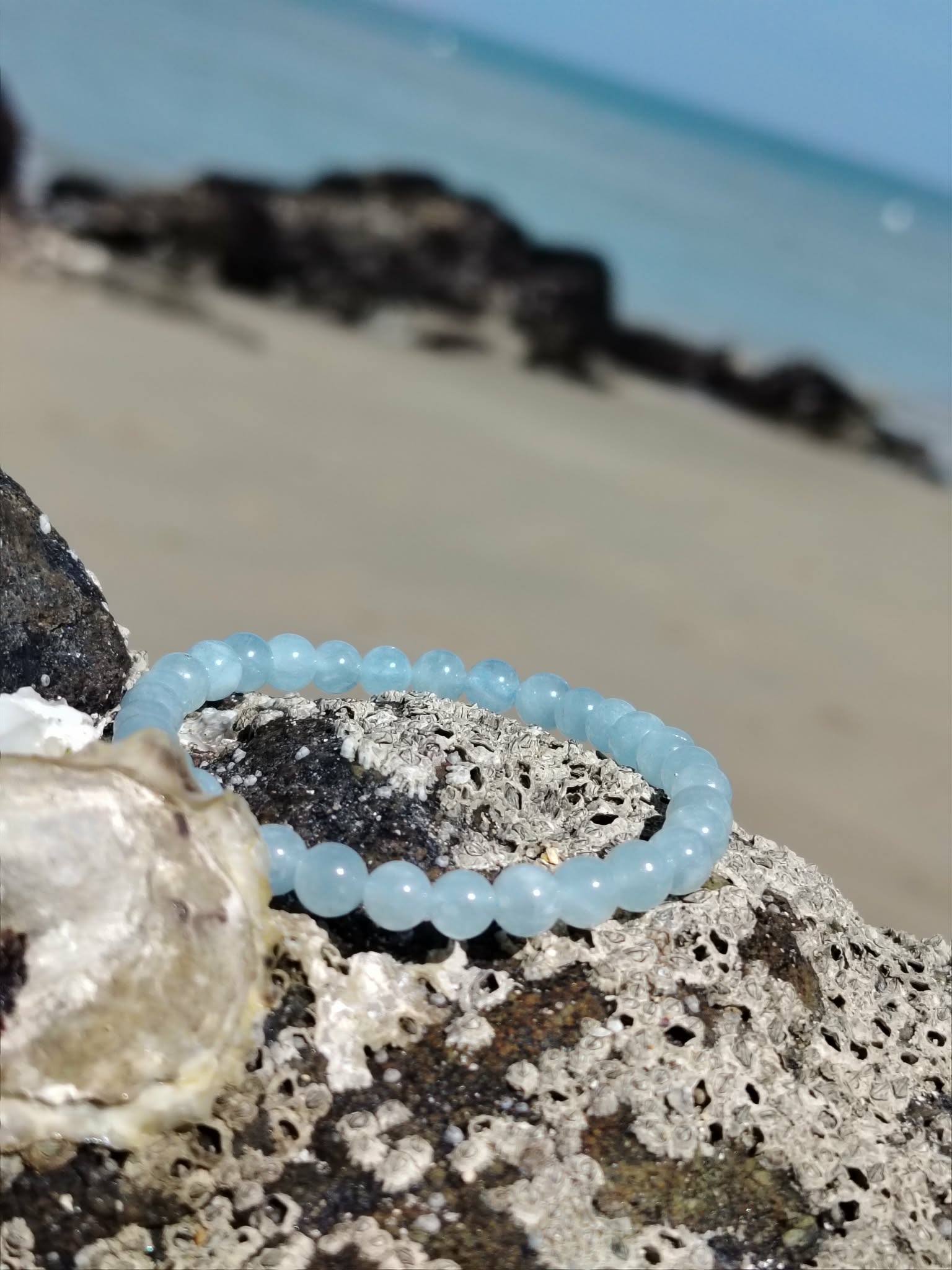Bracelet Aigue-Marine 6 mm en lumière naturelle sur décor côtier, perles bleu clair, apaisement du mental et énergie douce.