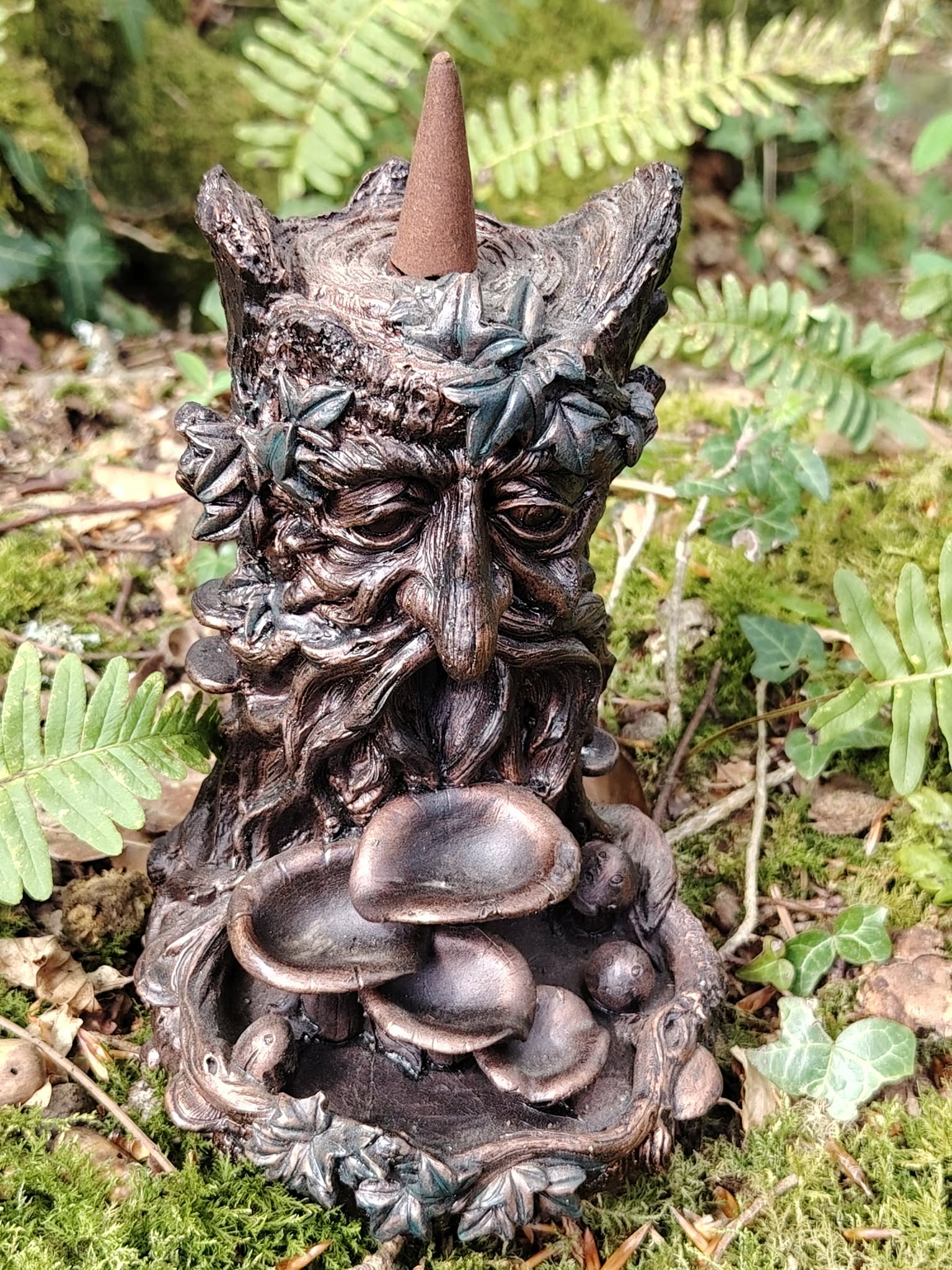 Brûleur d’encens à refoulement arbre en résine bronze posé en forêt, visage sculpté avec feuillage et coupelles en cascade pour diffusion de fumée.