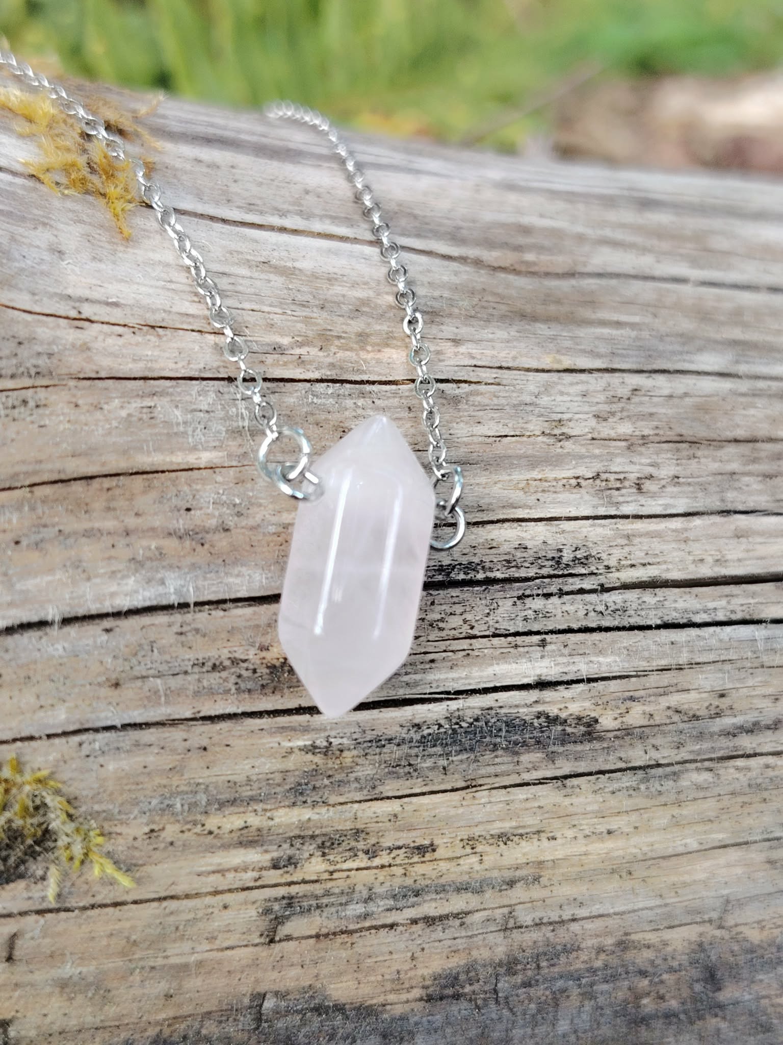 Collier en quartz rose sur chaîne argentée, pendentif allongé posé sur une branche avec mousse verte, évoquant tendresse, réconfort intérieur et harmonie affective.