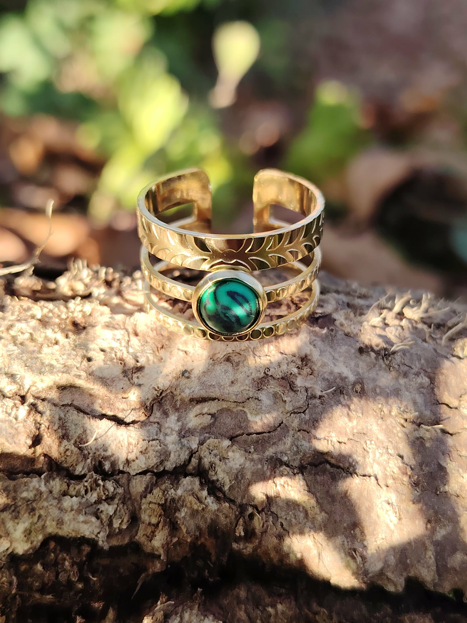 Bague pierre verte ajustable dorée en acier inoxydable sur écorce en forêt, anneau triple ligne et pierre verte effet malachite, élégance naturelle et harmonie intérieure.