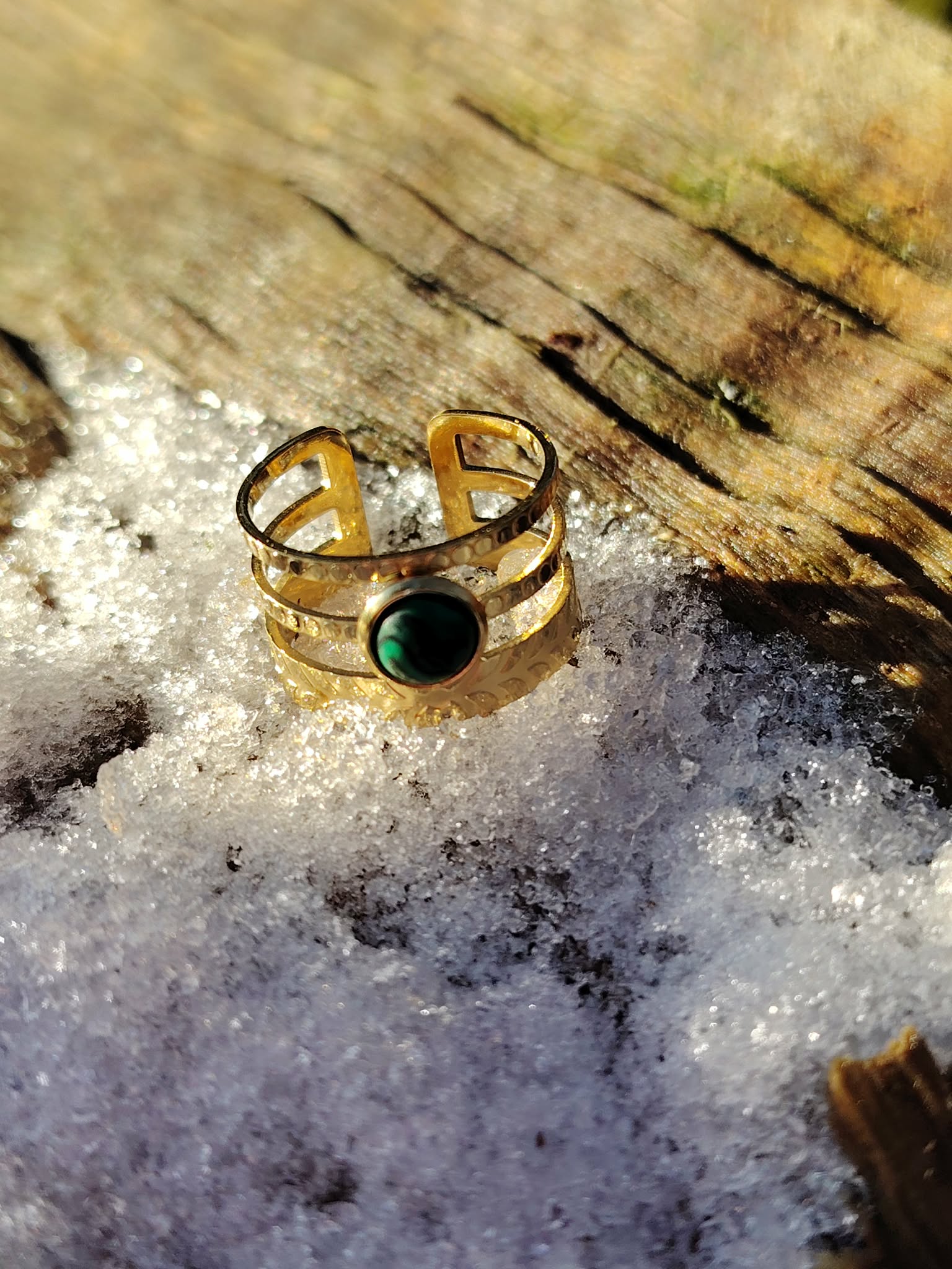 Bague pierre verte ajustable dorée photographiée sur bois et givre en extérieur, monture acier inoxydable et pierre verte profonde, clarté émotionnelle et énergie douce.
