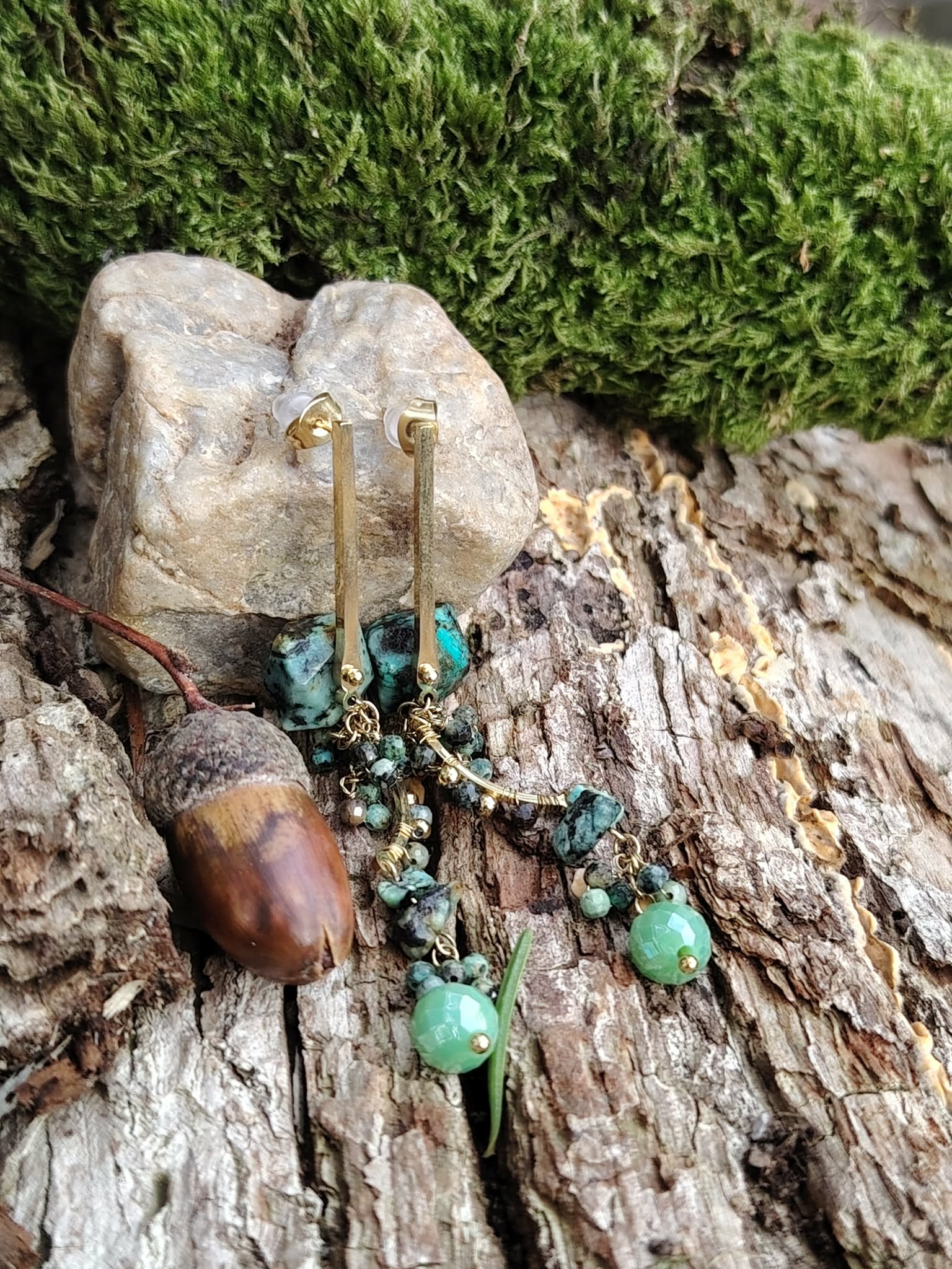 Boucles d’oreilles pendantes dorées en turquoise africaine sur écorce avec mousse et gland, perles marbrées vert d’eau et breloques délicates, calme intérieur et féminité naturelle.