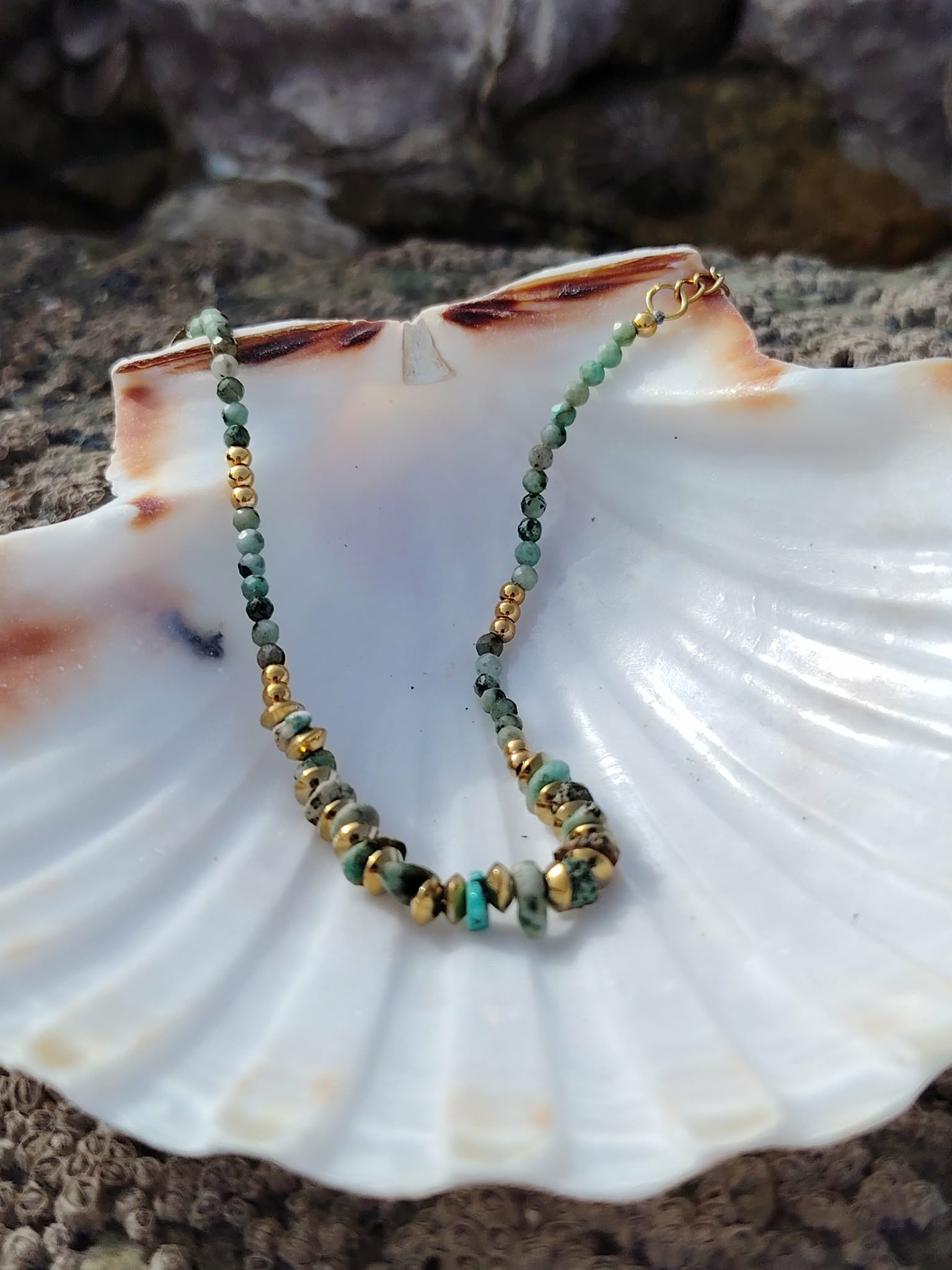 Bracelet doré en turquoise africaine et perles vert sauge sur écorce en forêt, nuances vert d’eau et bleu-vert, équilibre émotionnel et élégance lumineuse.