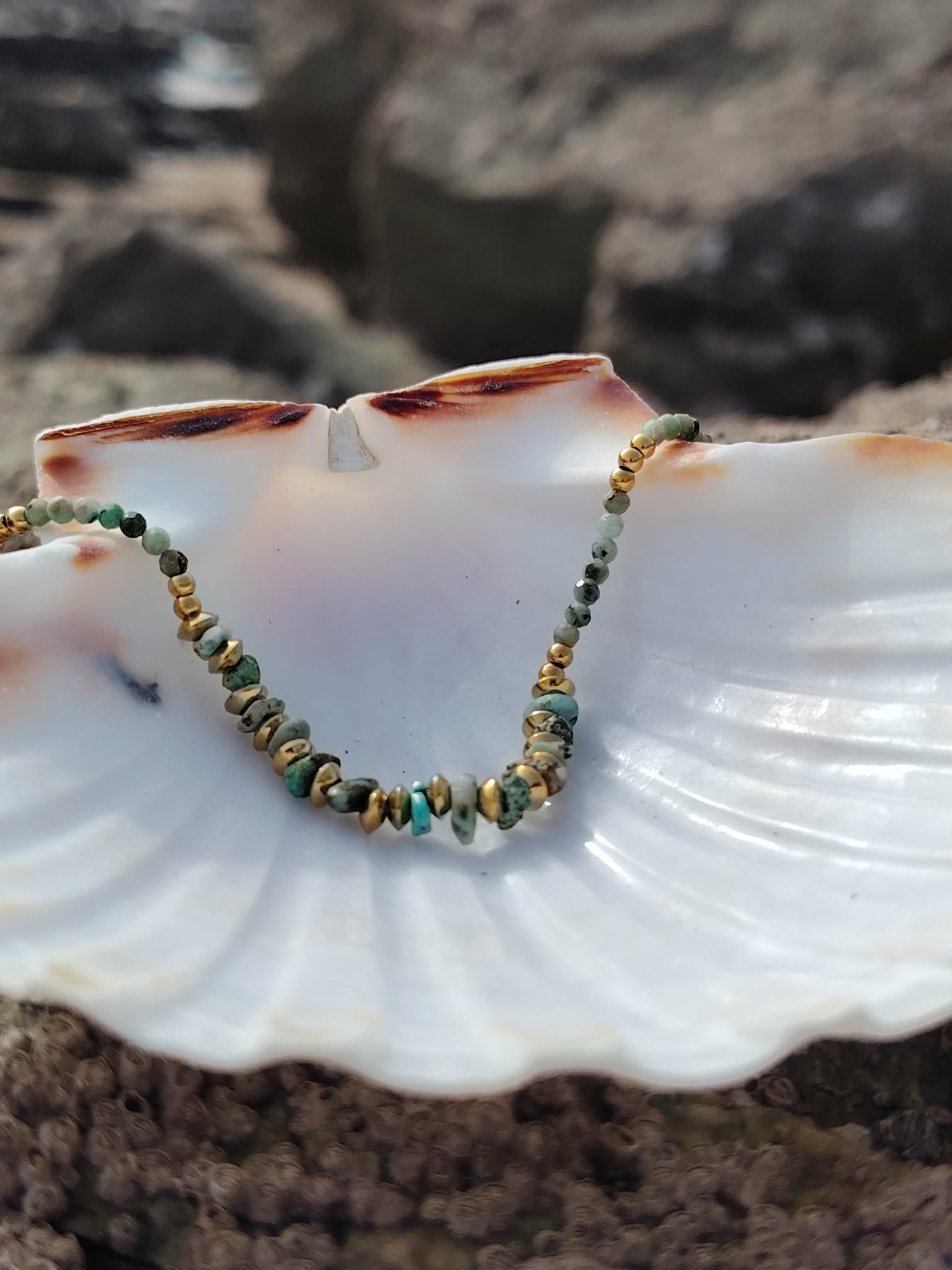 Bracelet fin doré avec turquoise africaine et perles vert sauge porté au poignet, bijou délicat aux tons naturels, calme émotionnel et style raffiné.