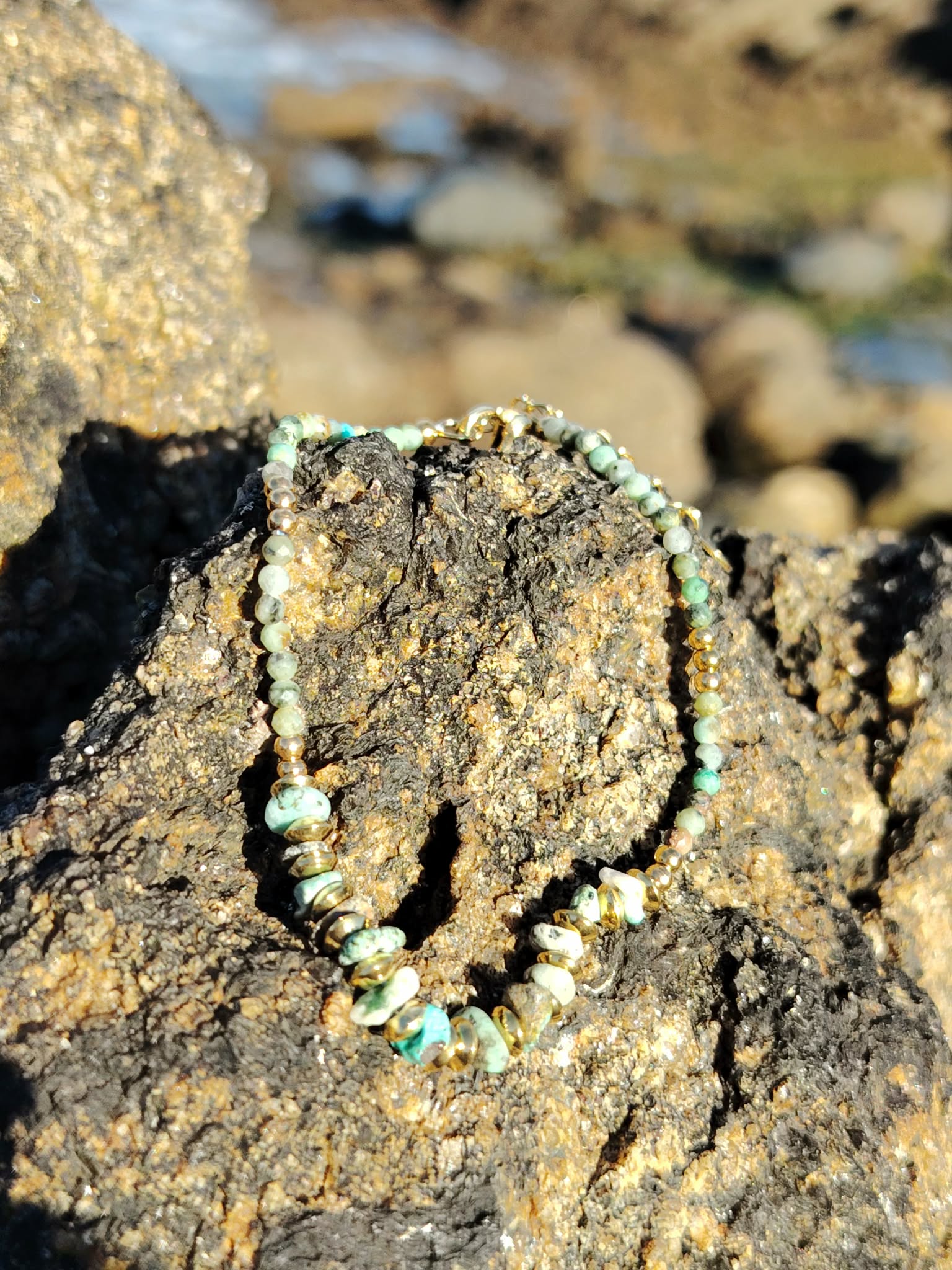 Bracelet doré turquoise africaine sur bois naturel en extérieur, perles vert sauge facettées et pierre marbrée, douceur intérieure et charme bohème.