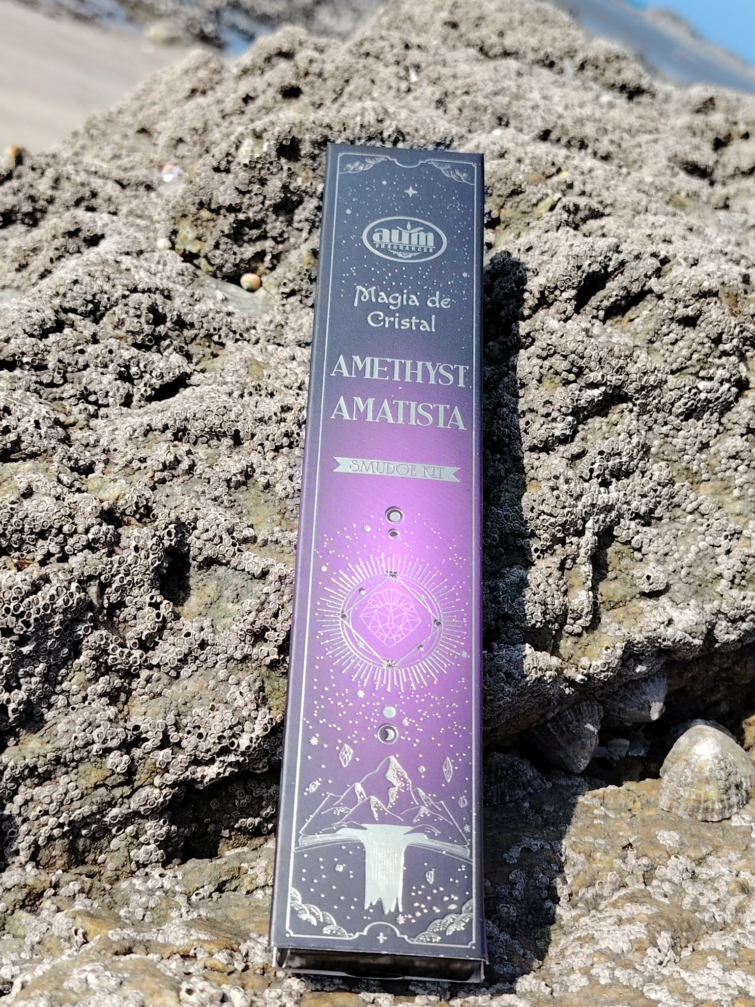 Boîte d’encens améthyste Aum Crystal Magic 20 g posée sur rocher coquillé au bord de mer en Bretagne, coffret violet ésotérique, ambiance apaisante et rituel parfumé.