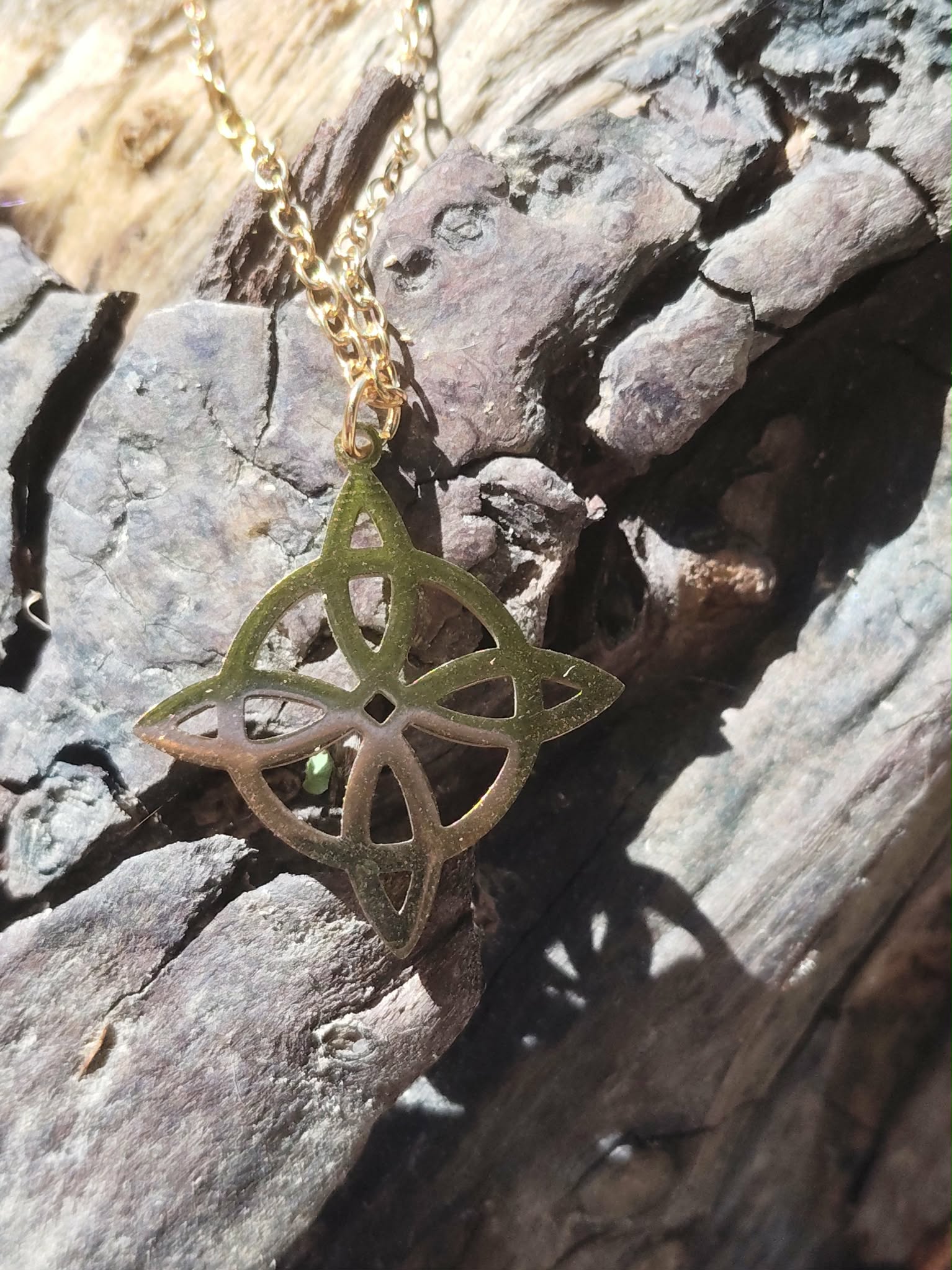 Pendentif nœud de sorcière en acier inoxydable doré en mise en situation, talisman symbolique lié à l’ancrage et à la force personnelle.