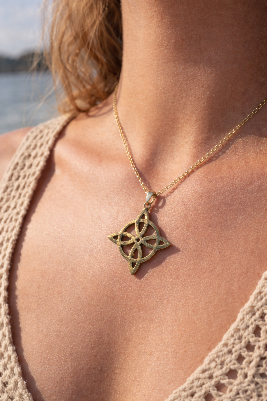 Pendentif nœud de sorcière doré porté au cou, bijou ésotérique raffiné associé à la protection et à la stabilité intérieure.