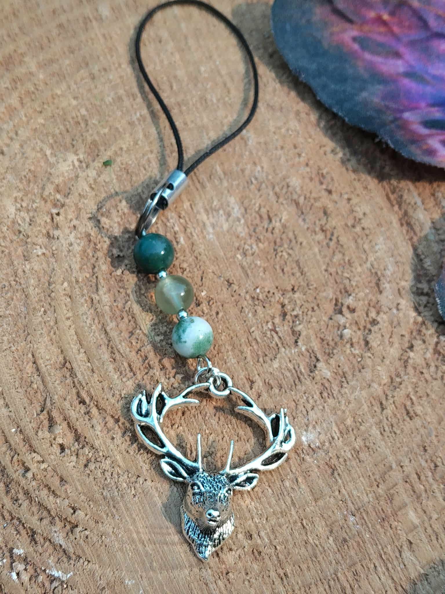 Bijou de téléphone Éole en gros plan, perles bleu clair et détails argentés, création symbolique évoquant le calme, la fluidité et l’équilibre intérieur.