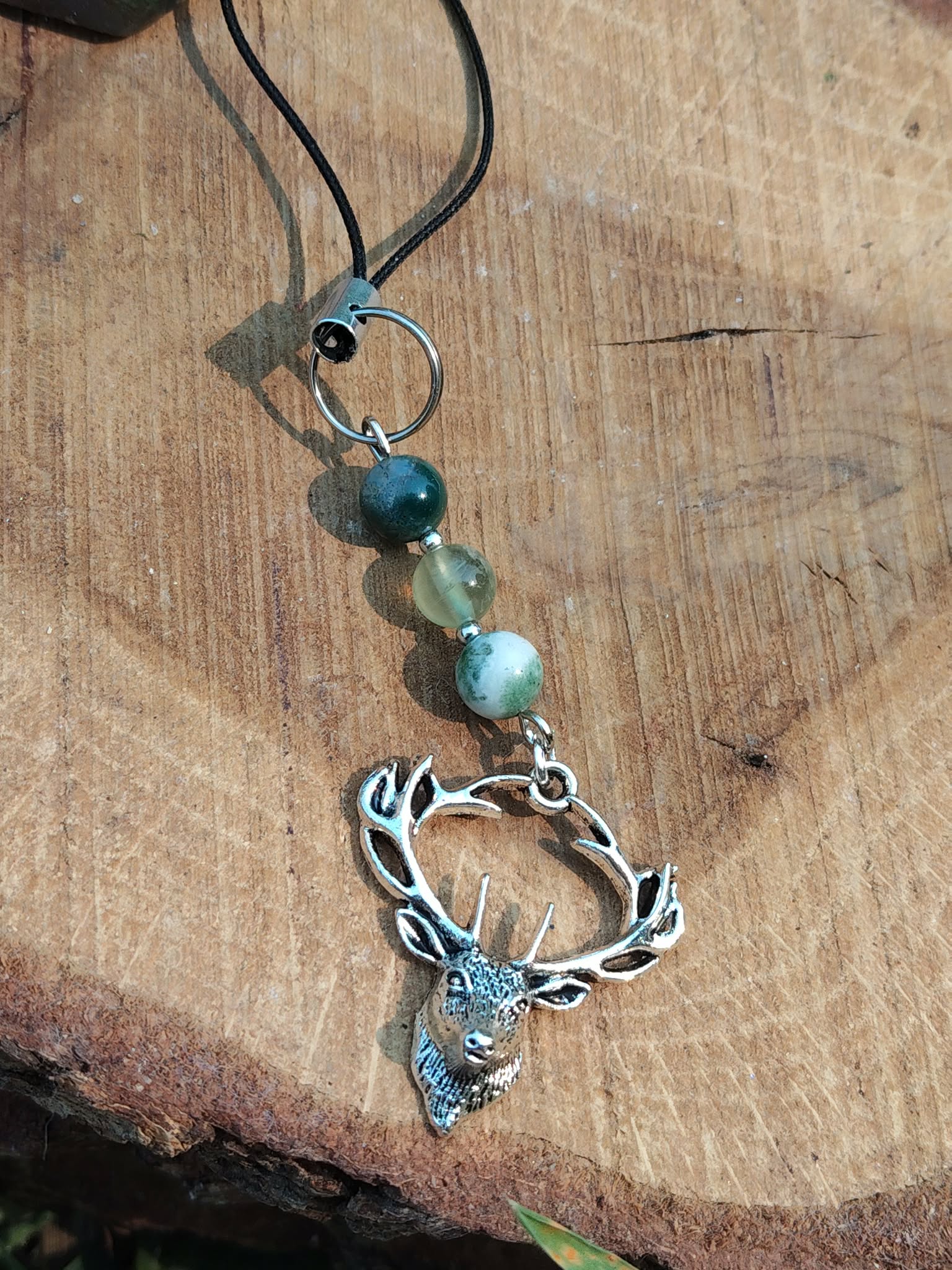 Bijou de téléphone Éole présenté de près avec perles bleues et argentées, accessoire délicat inspirant détente, clarté et respiration intérieure.