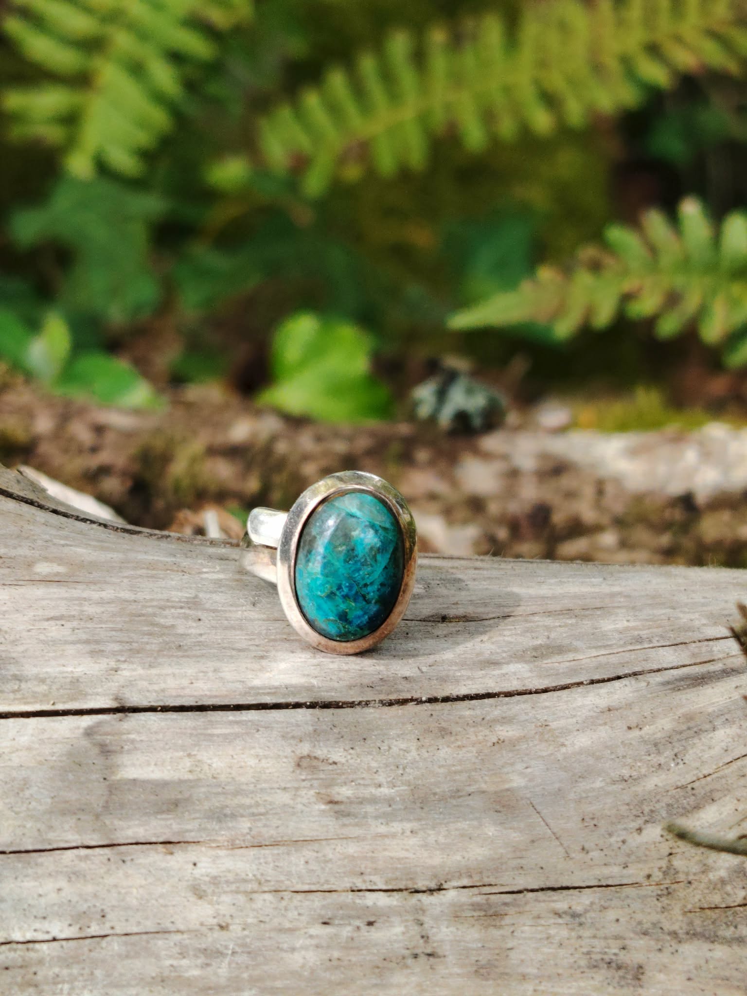 Bague chrysocolle argent 925 réglable sur bois clair avec feuillage en arrière-plan, bijou pierre naturelle bleu vert, apaisement, communication et équilibre émotionnel.