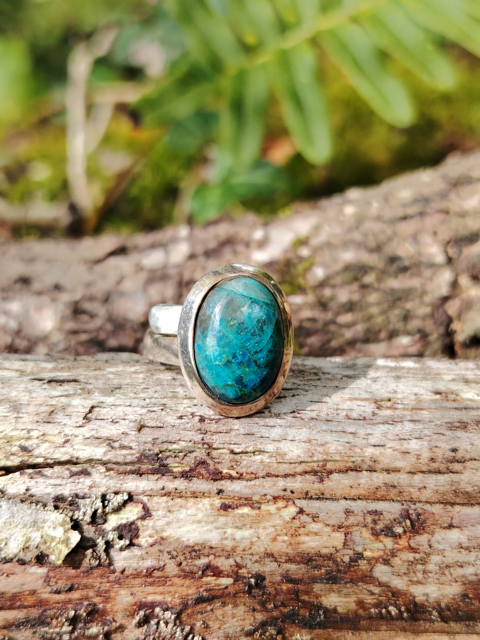Bague chrysocolle argent 925 réglable posée sur bois en extérieur, pierre ovale bleu vert naturelle.
