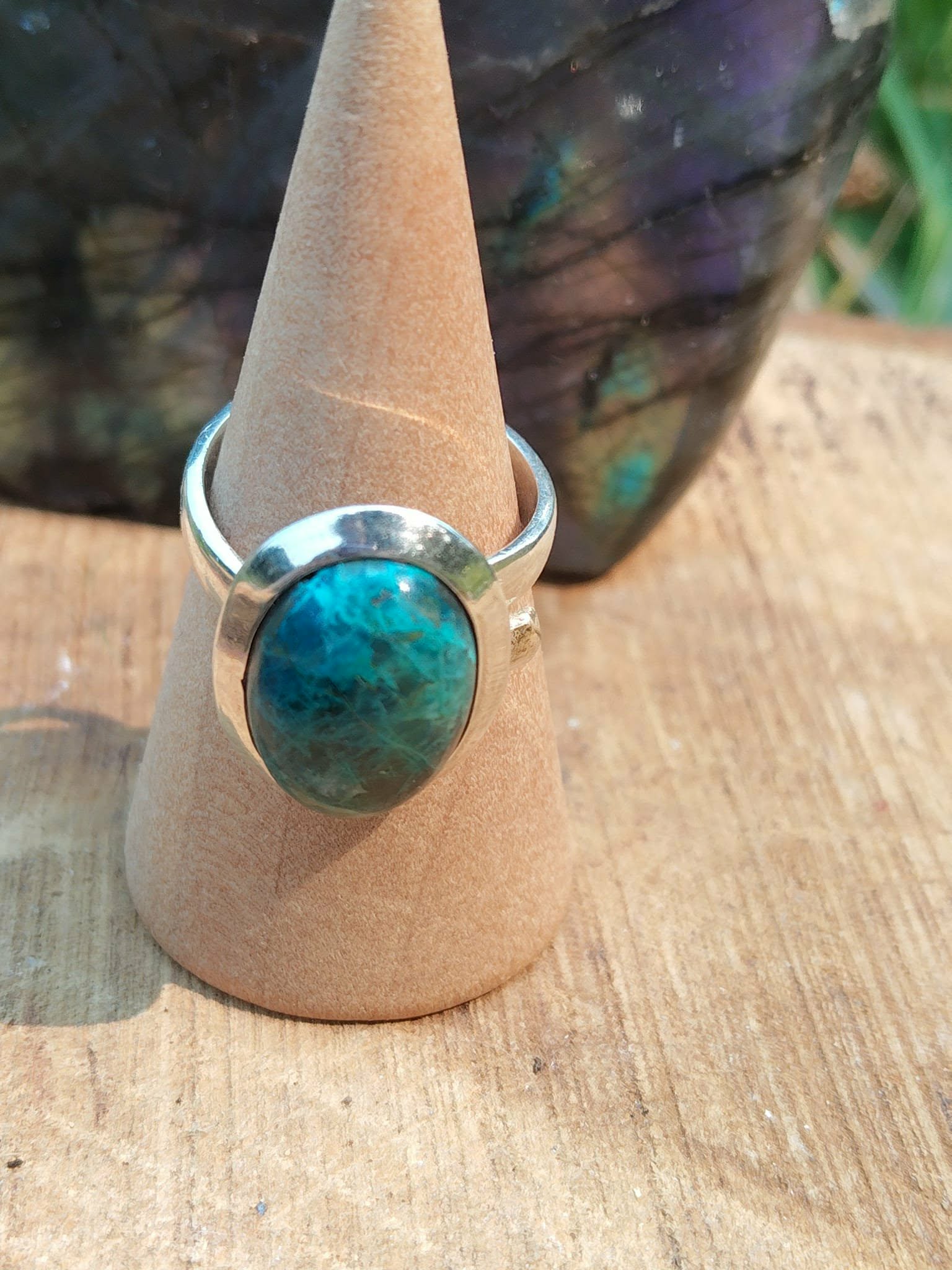 Bague chrysocolle argent 925 réglable sur cône en bois devant pierre sombre, cabochon bleu vert, douceur intérieure, expression sincère et sérénité.