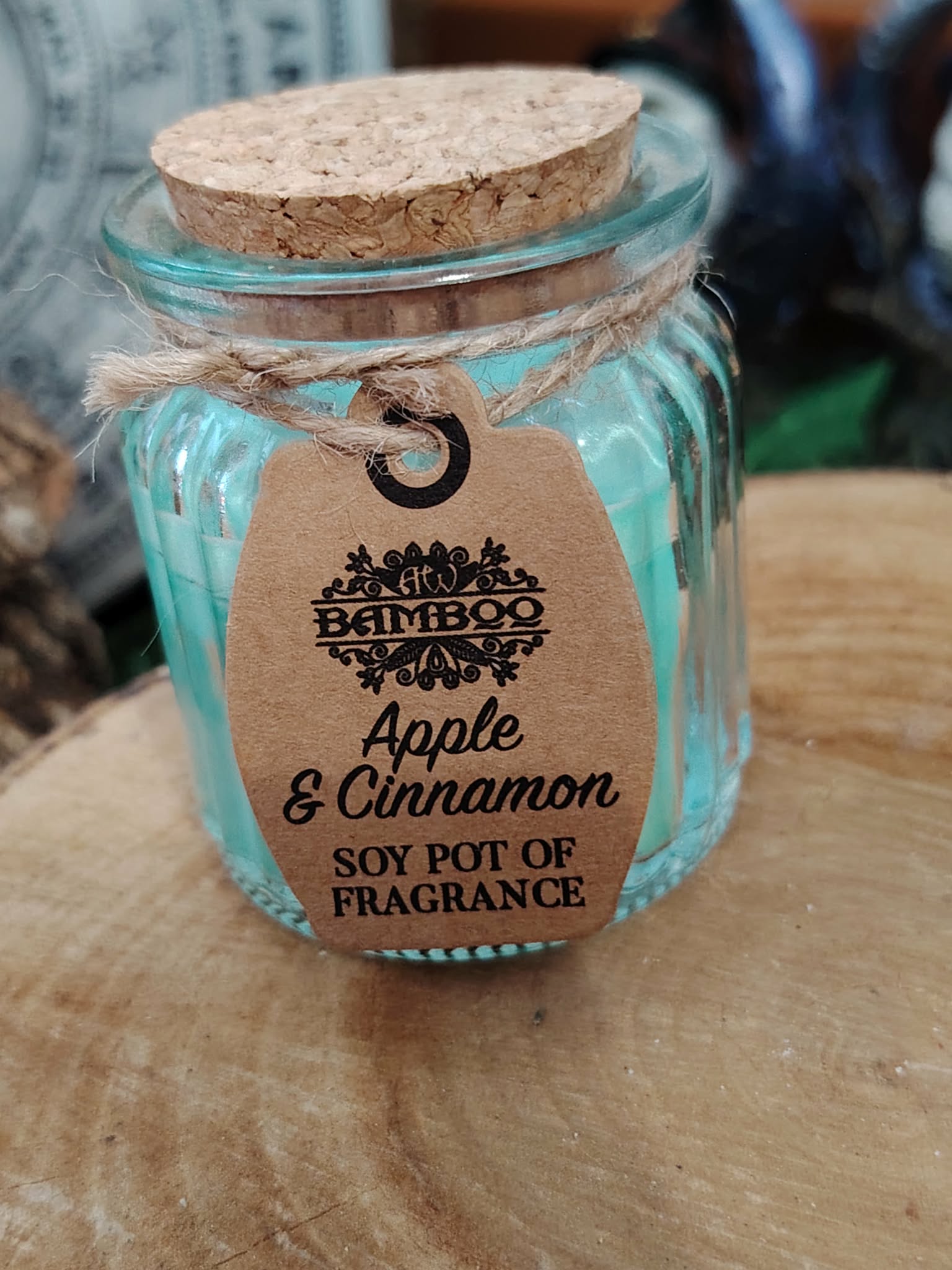 Bougie parfumée Pomme Cannelle en cire de soja sur support en bois, pot en verre avec couvercle en liège, senteur gourmande et atmosphère réconfortante.