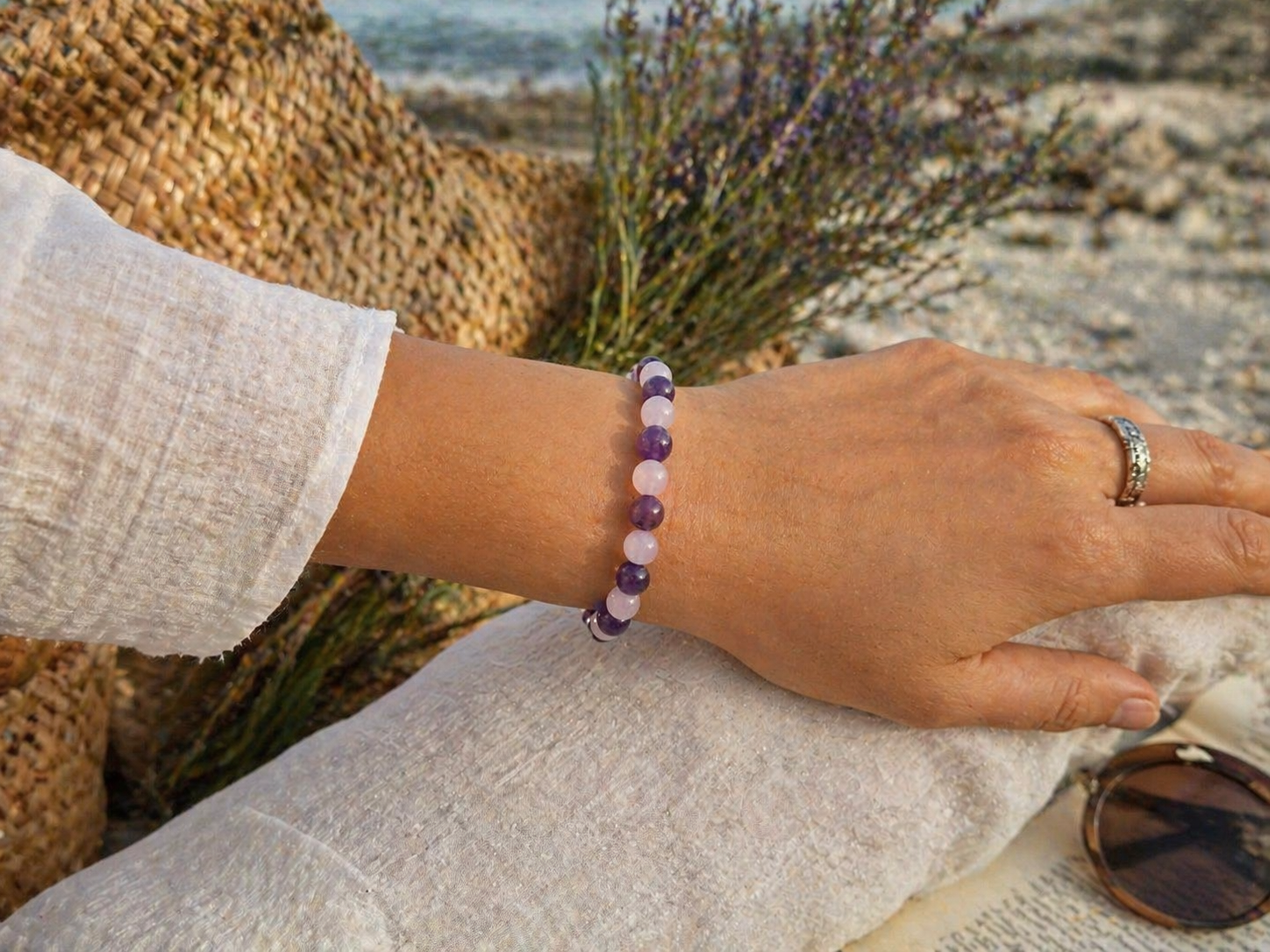 Bracelet Lépidolite Kunzite porté au poignet en extérieur près de la mer en Bretagne, bijou en pierres naturelles aux tons violets et rosés.