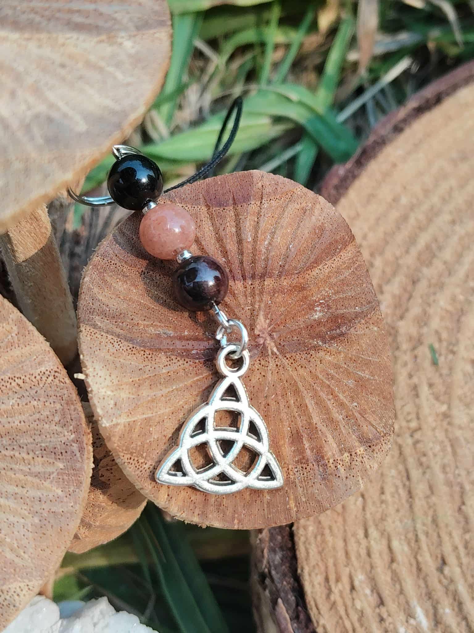 Bijou de téléphone Viking Triquetra avec perles rose poudré et noires, pendentif celtique argenté, protection symbolique et équilibre émotionnel.