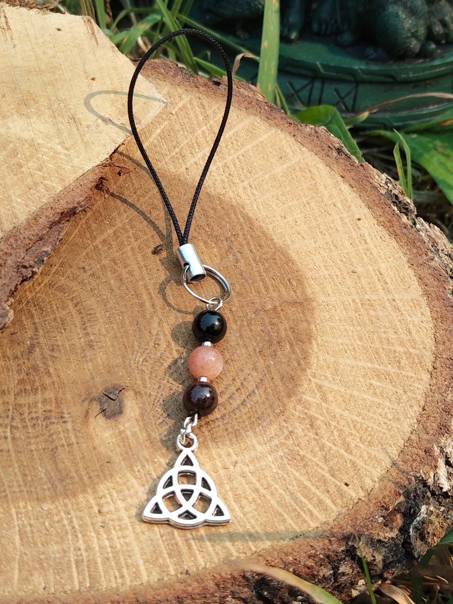 Bijou de téléphone Viking Triquetra avec perles rose poudré et noires, pendentif celtique argenté, protection symbolique et équilibre émotionnel.