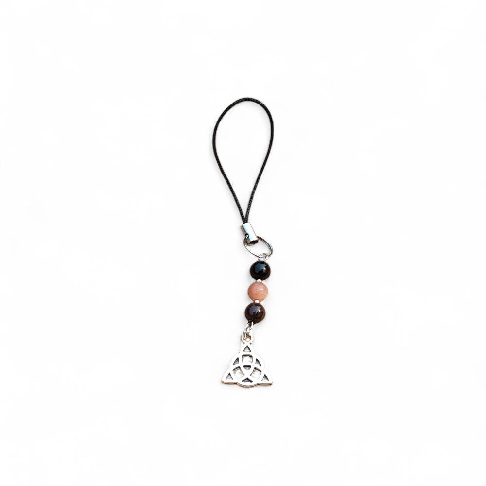 Bijou de téléphone Viking Triquetra avec perles noires et rose poudré sur fond clair, accessoire spirituel de protection, ancrage et harmonie.
