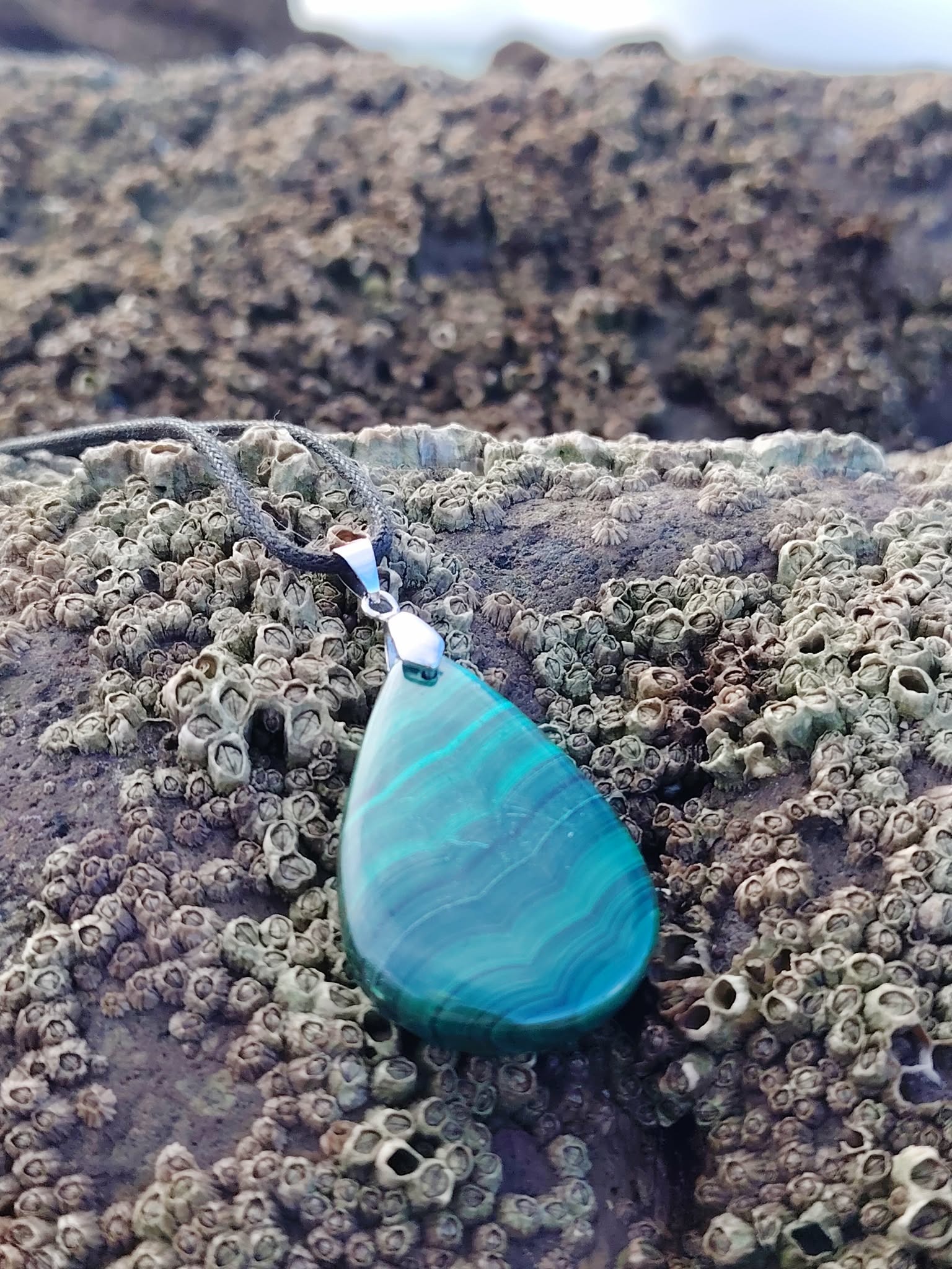 Pendentif malachite en goutte porté en extérieur, pierre naturelle verte aux marbrures intenses, ancrage, protection et harmonie intérieure.