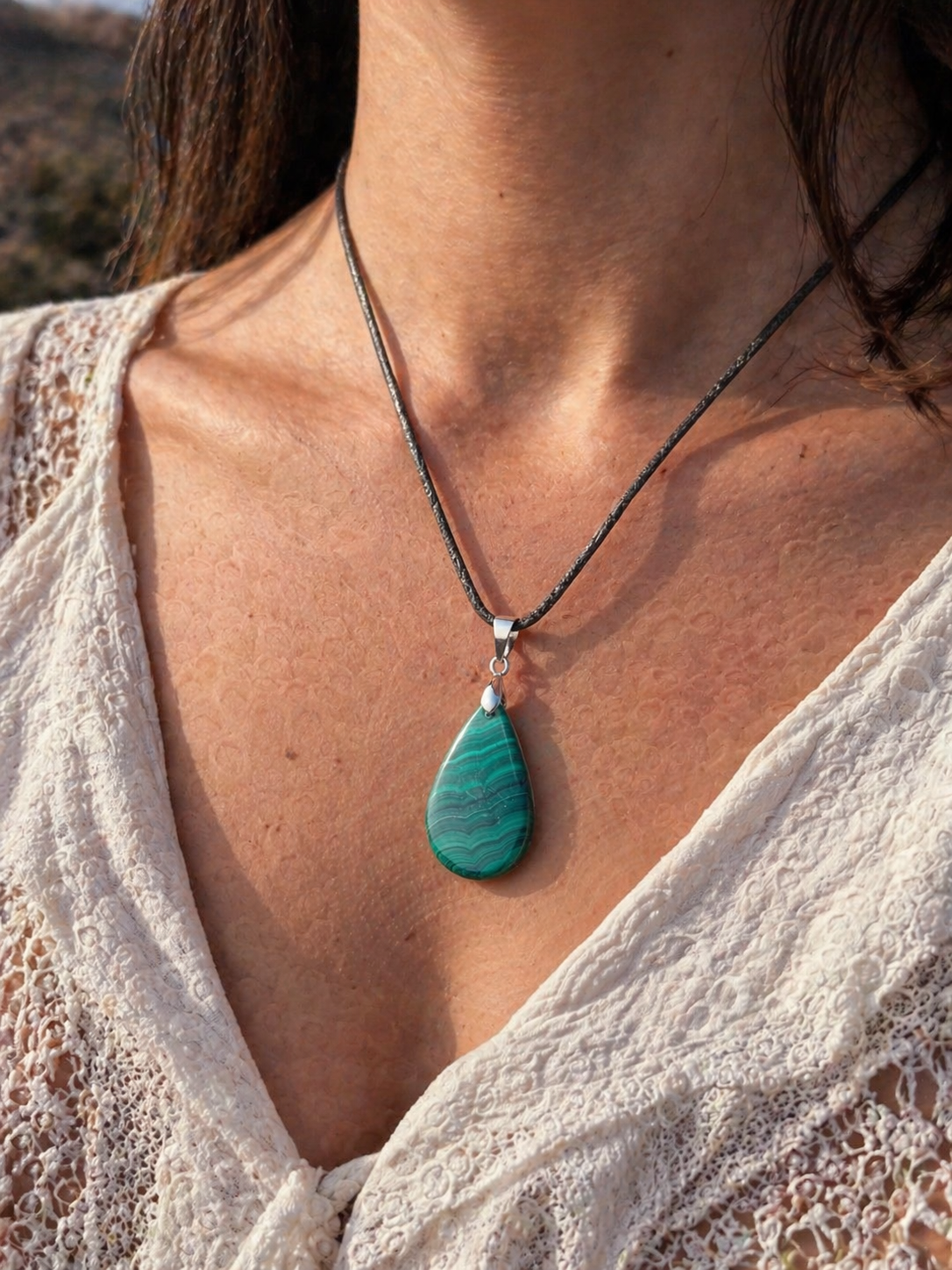 Pendentif malachite naturelle porté au cou, pierre goutte vert profond sur cordon noir, apaisement, confiance et transformation personnelle.