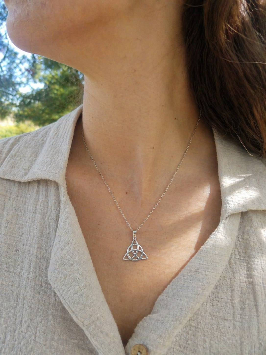Pendentif Triquetra argent 925 porté sur peau en extérieur, bijou celtique lumineux aux lignes ajourées, ancrage, sérénité et force intérieure.