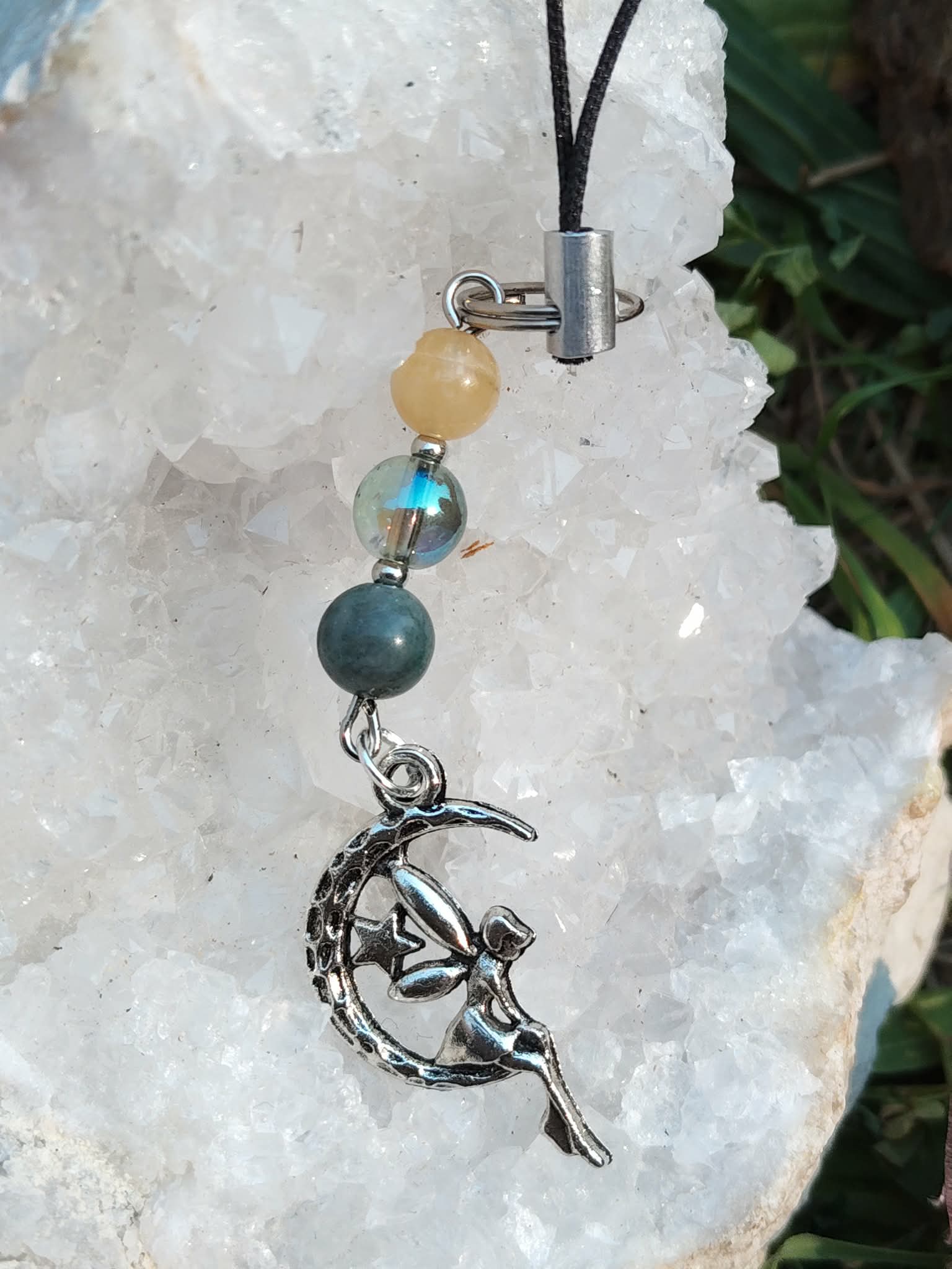Création Magic Gaïa pour téléphone avec lune fée décorative, agate mousse verte, Aqua Aura brillante et calcite jaune sur un amas de quartz , style doux et enchanteur.