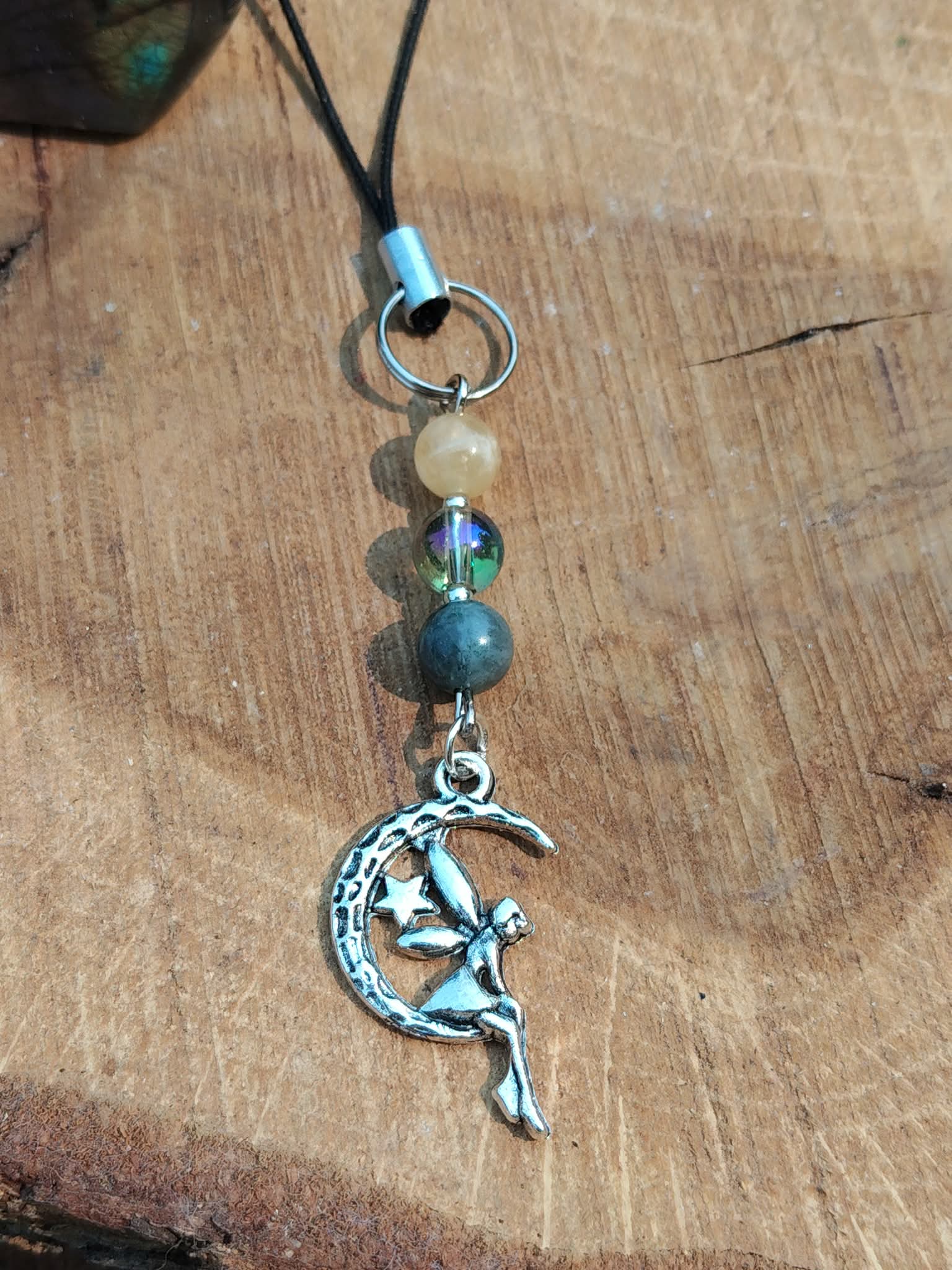 Bijou de téléphone Lune Féerique avec pierres naturelles et élément central irisé, une création élégante et poétique qui associe la beauté de la nature à une touche lumineuse et raffinée.